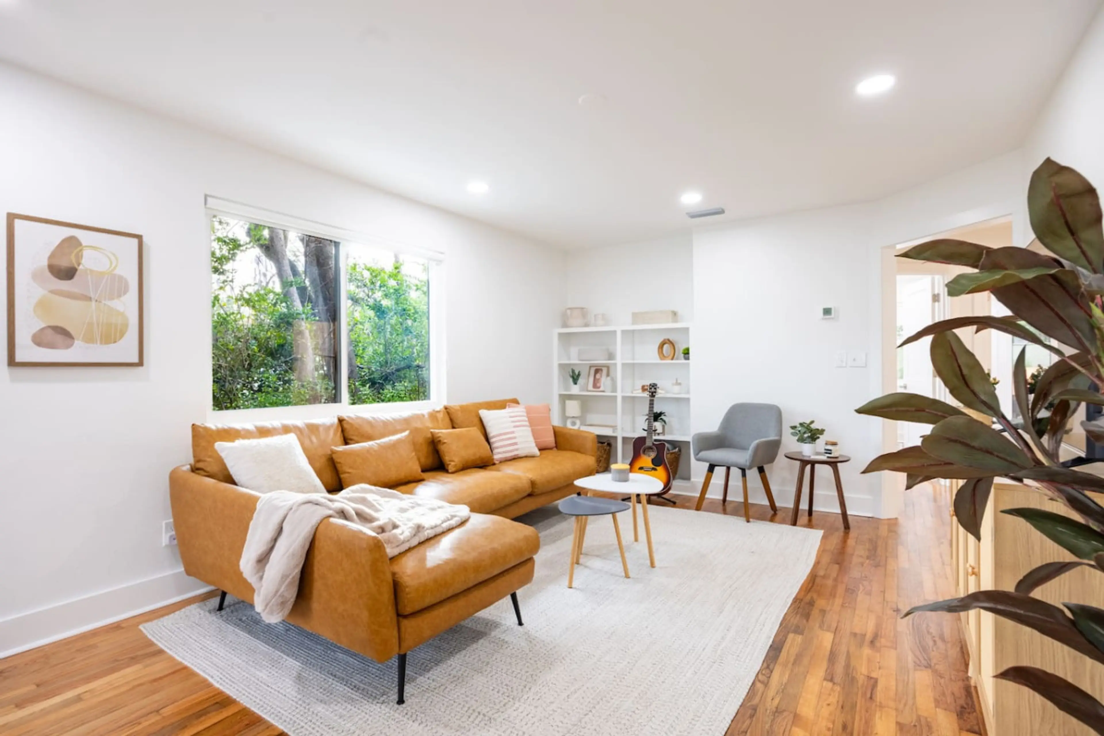 Spacious and modern living room with a comfortable sofa, chic furnishings, and large windows for a fresh, airy feel.