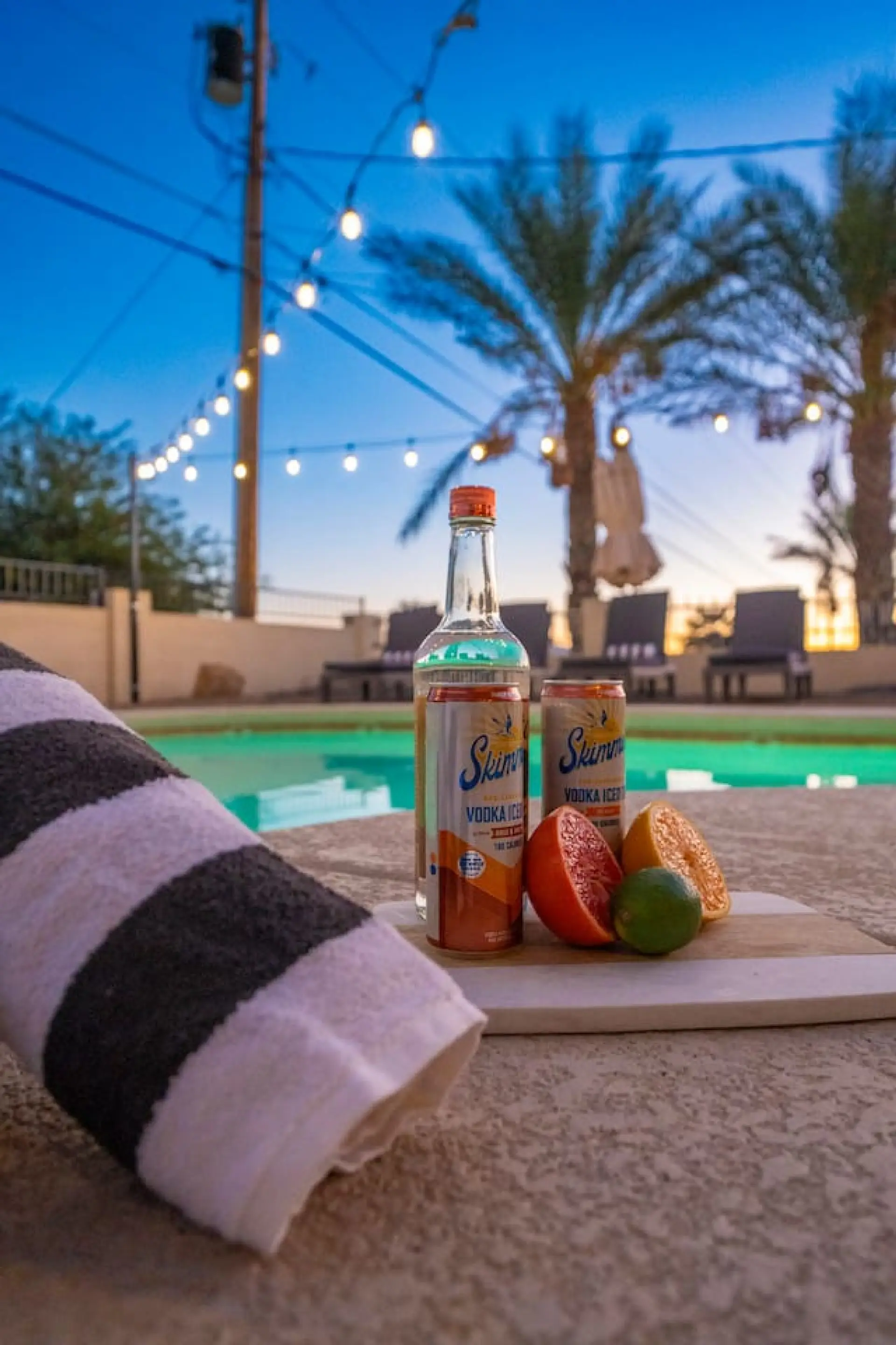 Twilight poolside moment — glowing pool, string lights, palm silhouettes. The adults' reward after a long day on the water.