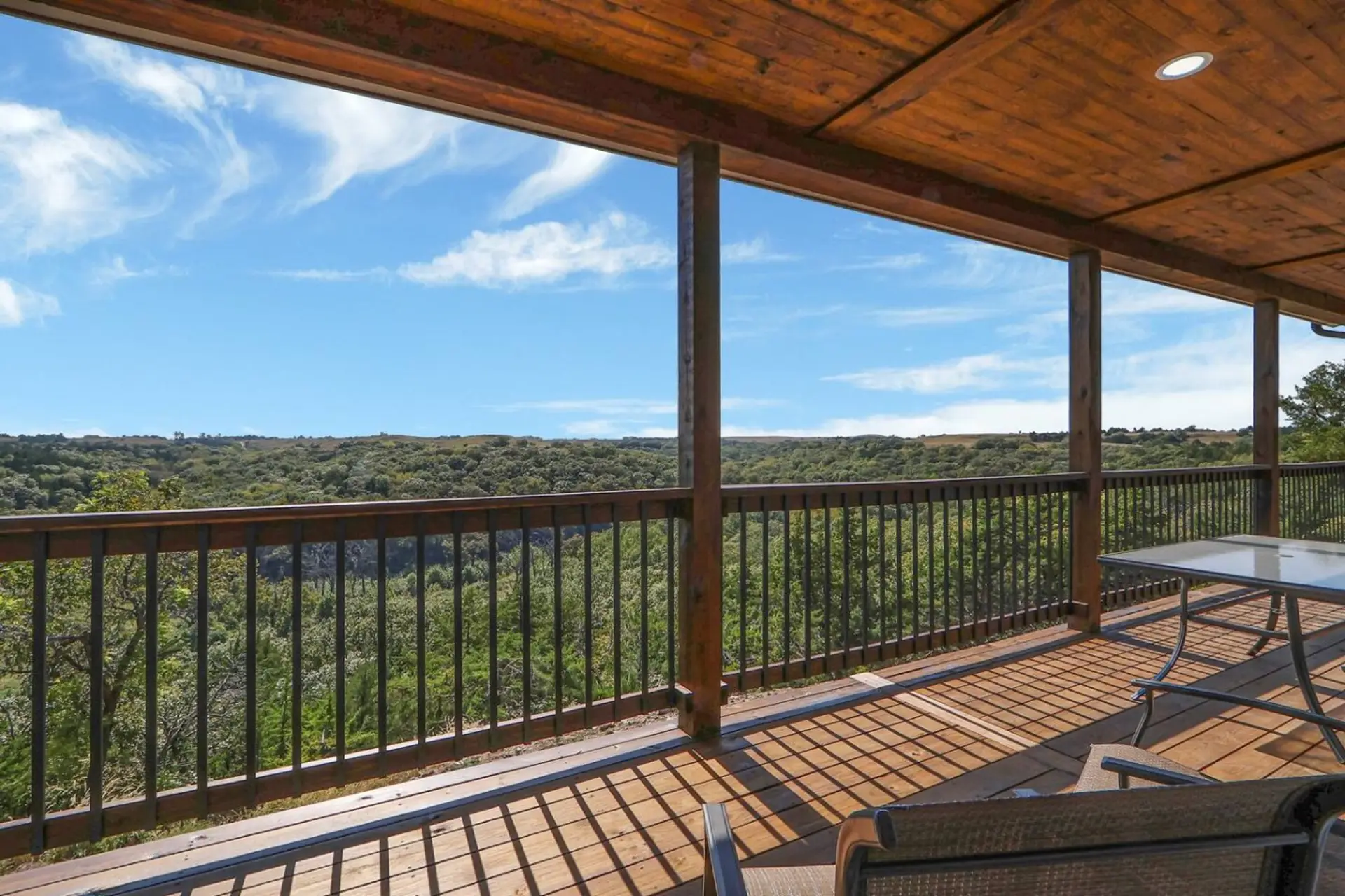 Large back deck with chairs, a table, and a grill