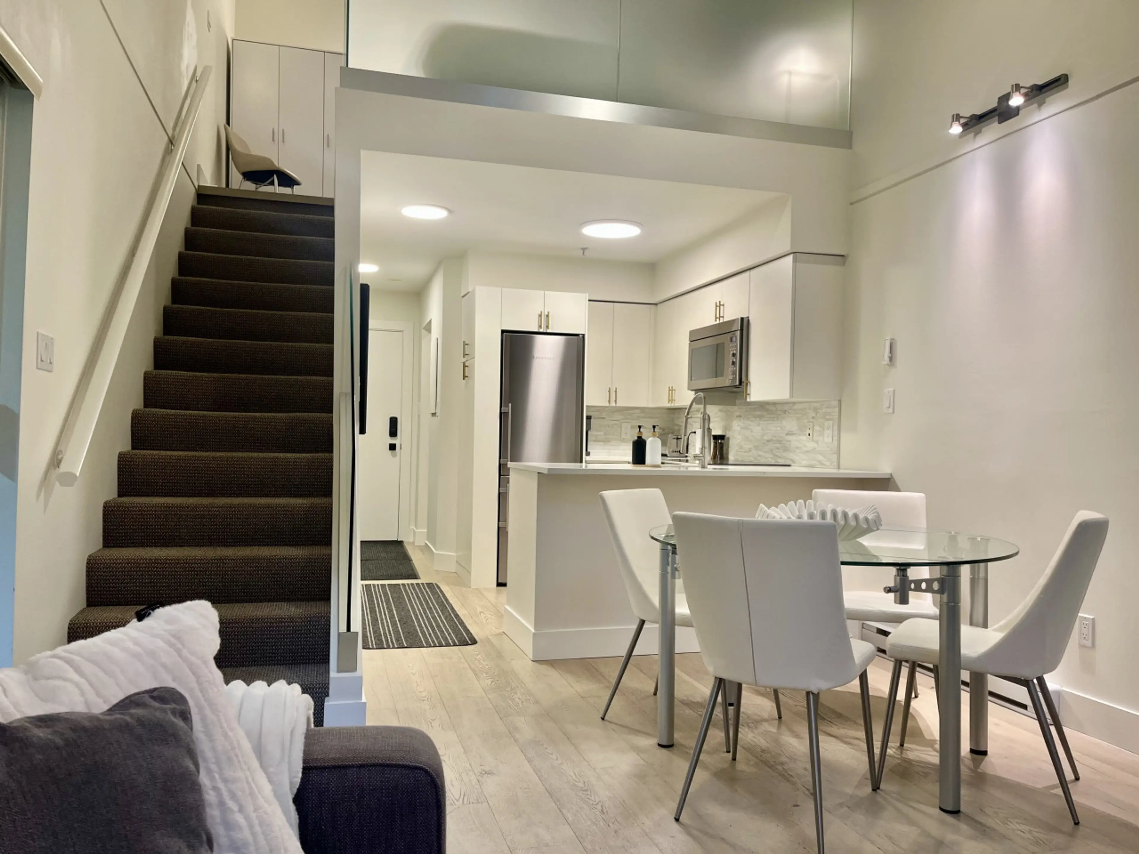 Dining table and kitchen with the entrance to the front door. Stairs on the left lead upstairs.