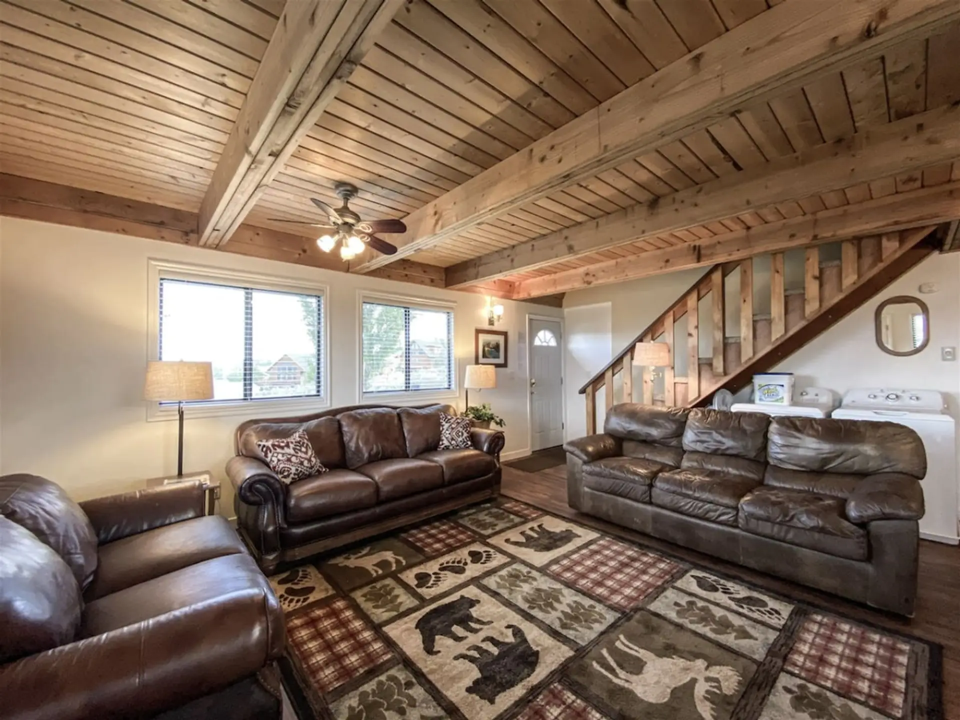Cozy cabin living room with rustic charm, comfy leather seating, and warm wood beam ceilings