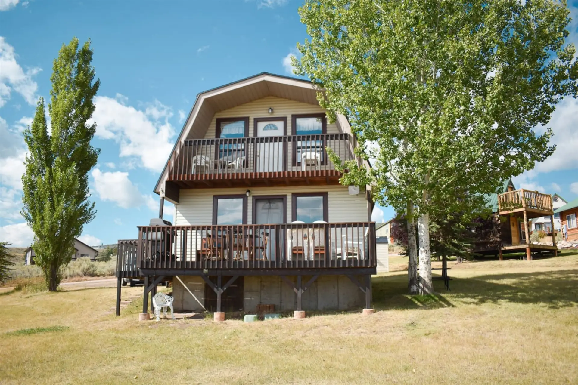 Charming two-story cabin with dual decks, surrounded by trees and open skies—perfect for relaxing getaways