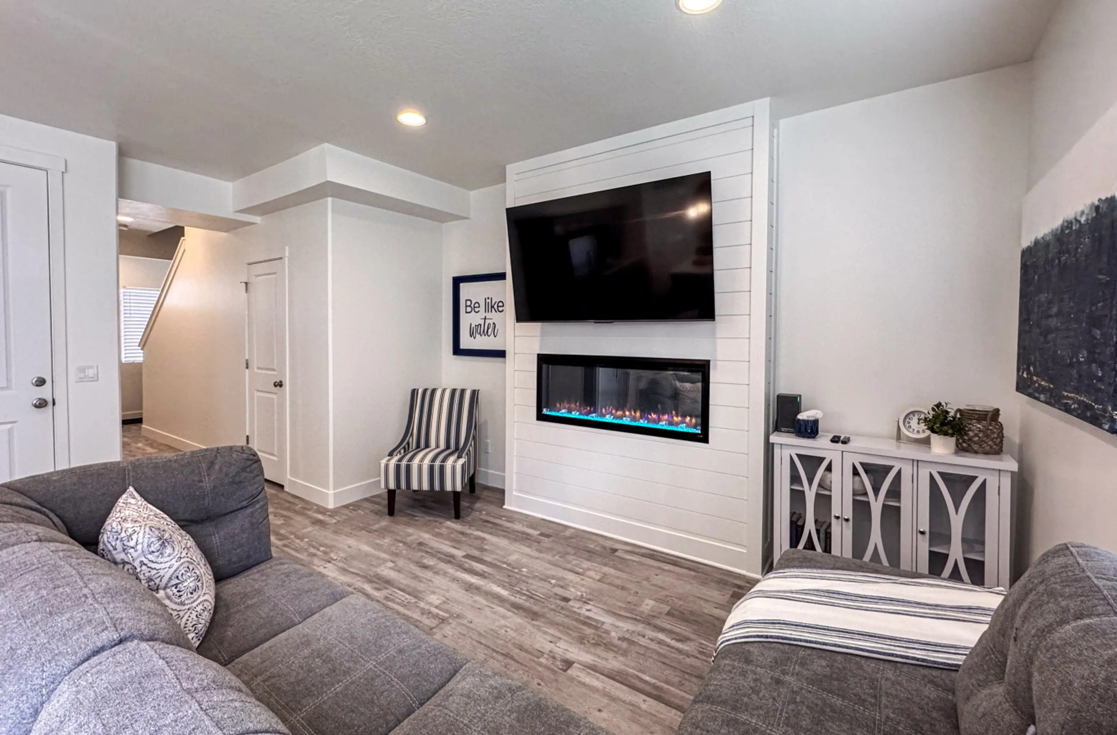 Elegant living space with electric fireplace, wall-mounted TV, and cozy seating for relaxation.