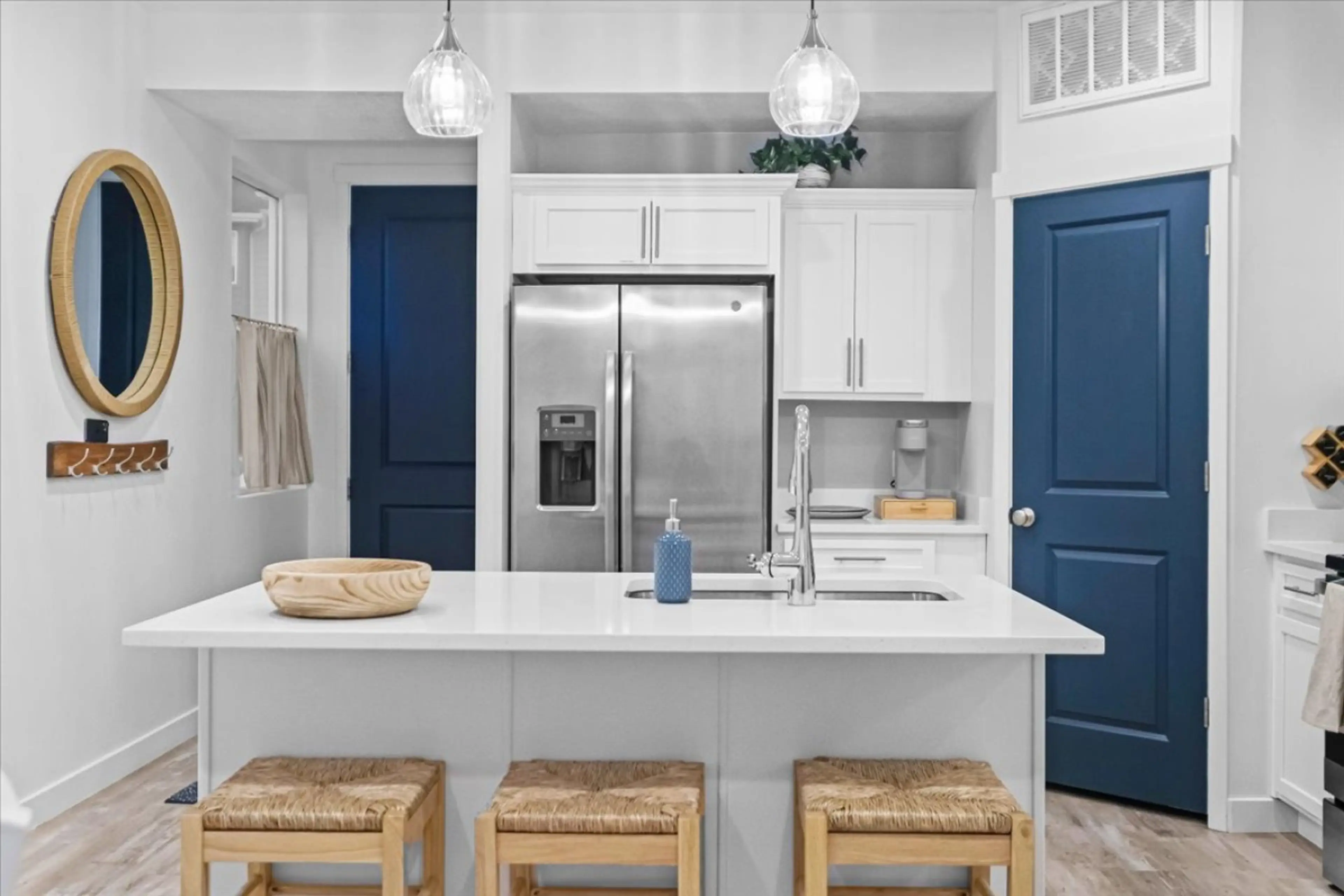 Bright, modern kitchen featuring cozy natural accents, crisp white cabinetry, and bold navy doors