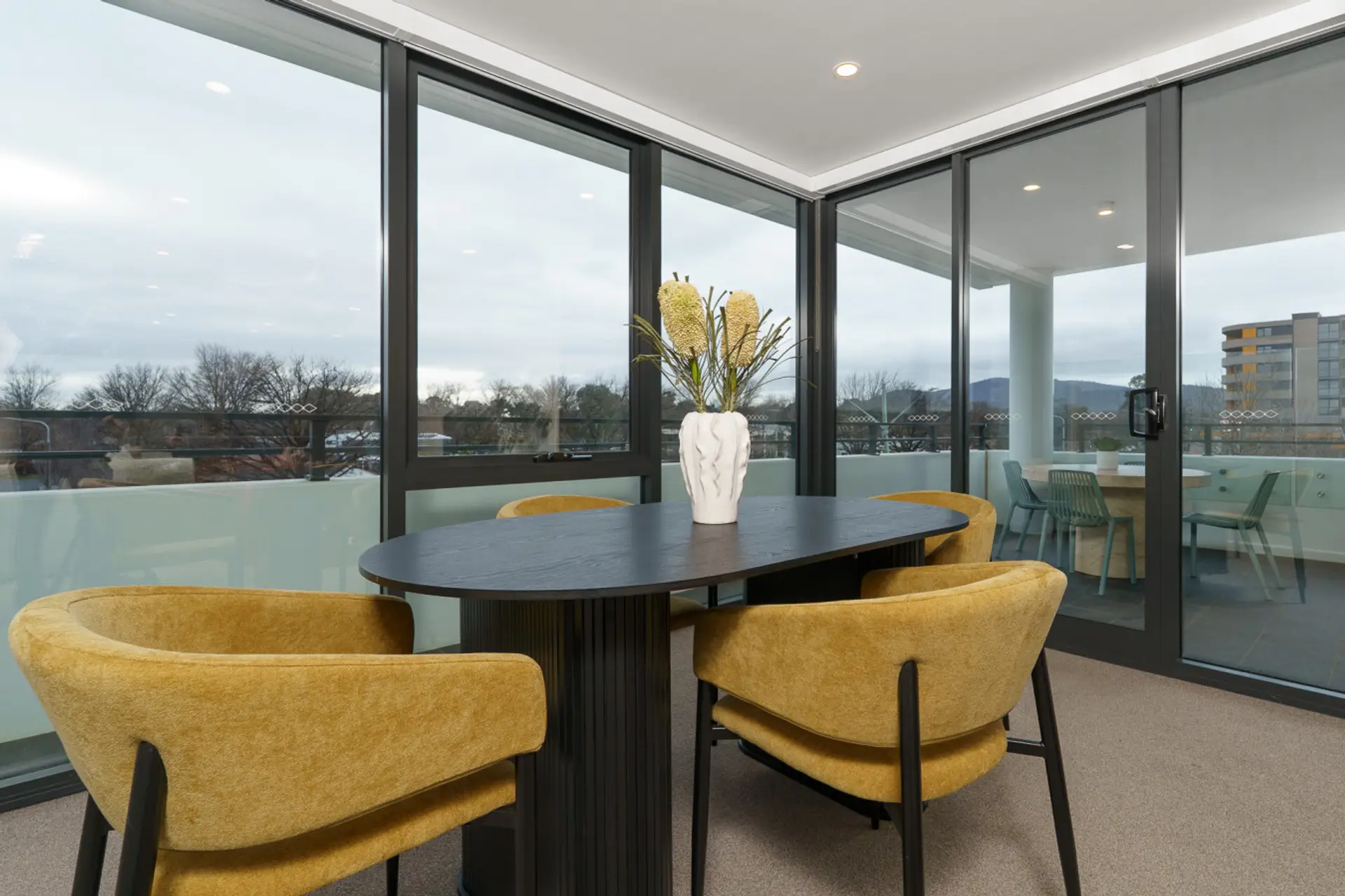 Modern dining space with mustard chairs and scenic balcony views.