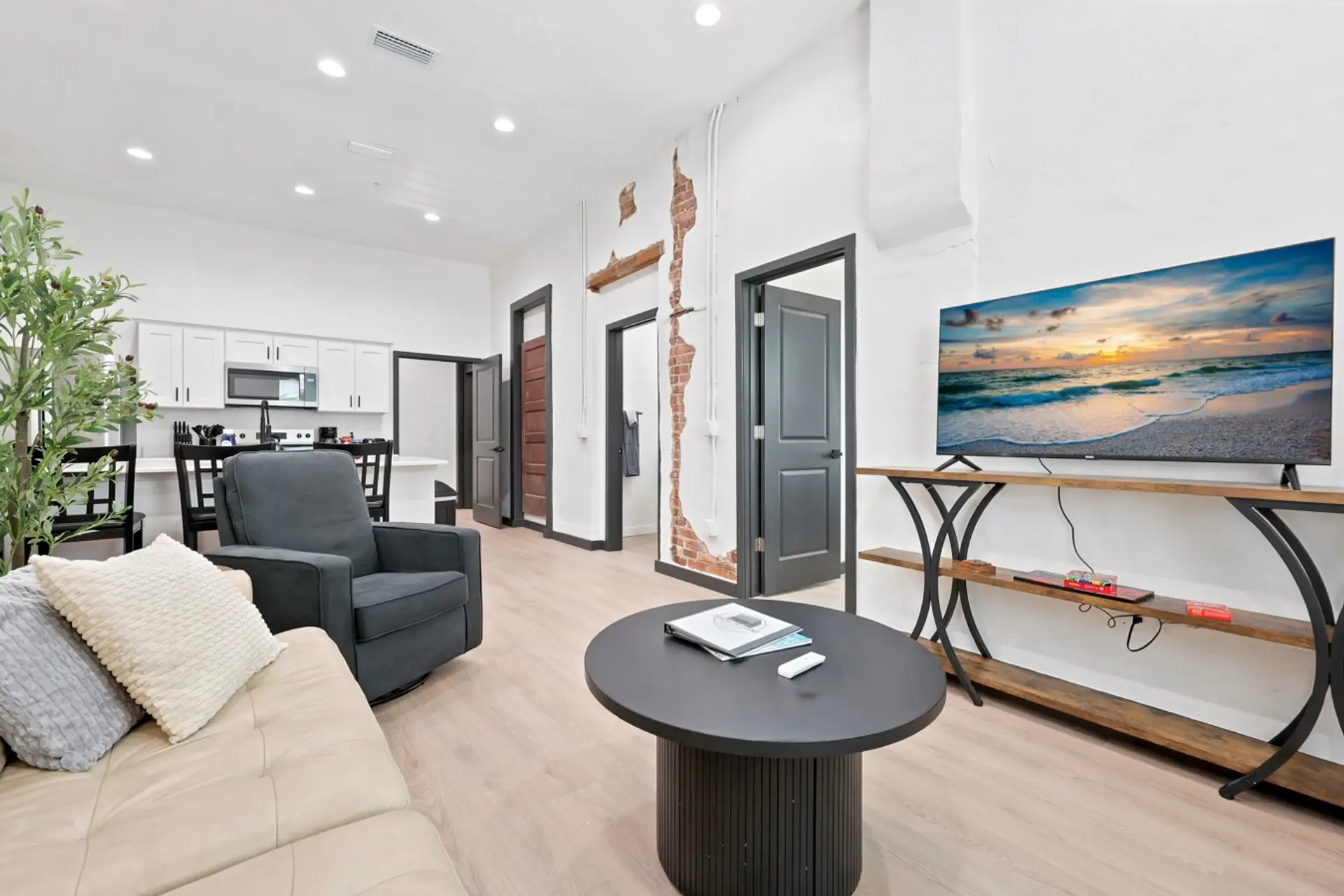 Living Room: Bright, inviting living room with soaring ceilings, comfortable seating, large TV, and charming exposed-brick details.