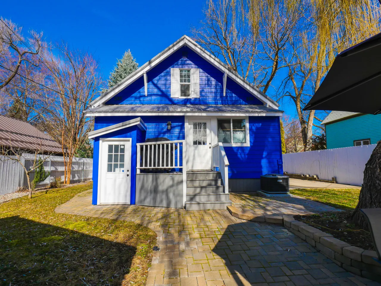 Bright blue downtown house with white trim and a mature shade tree