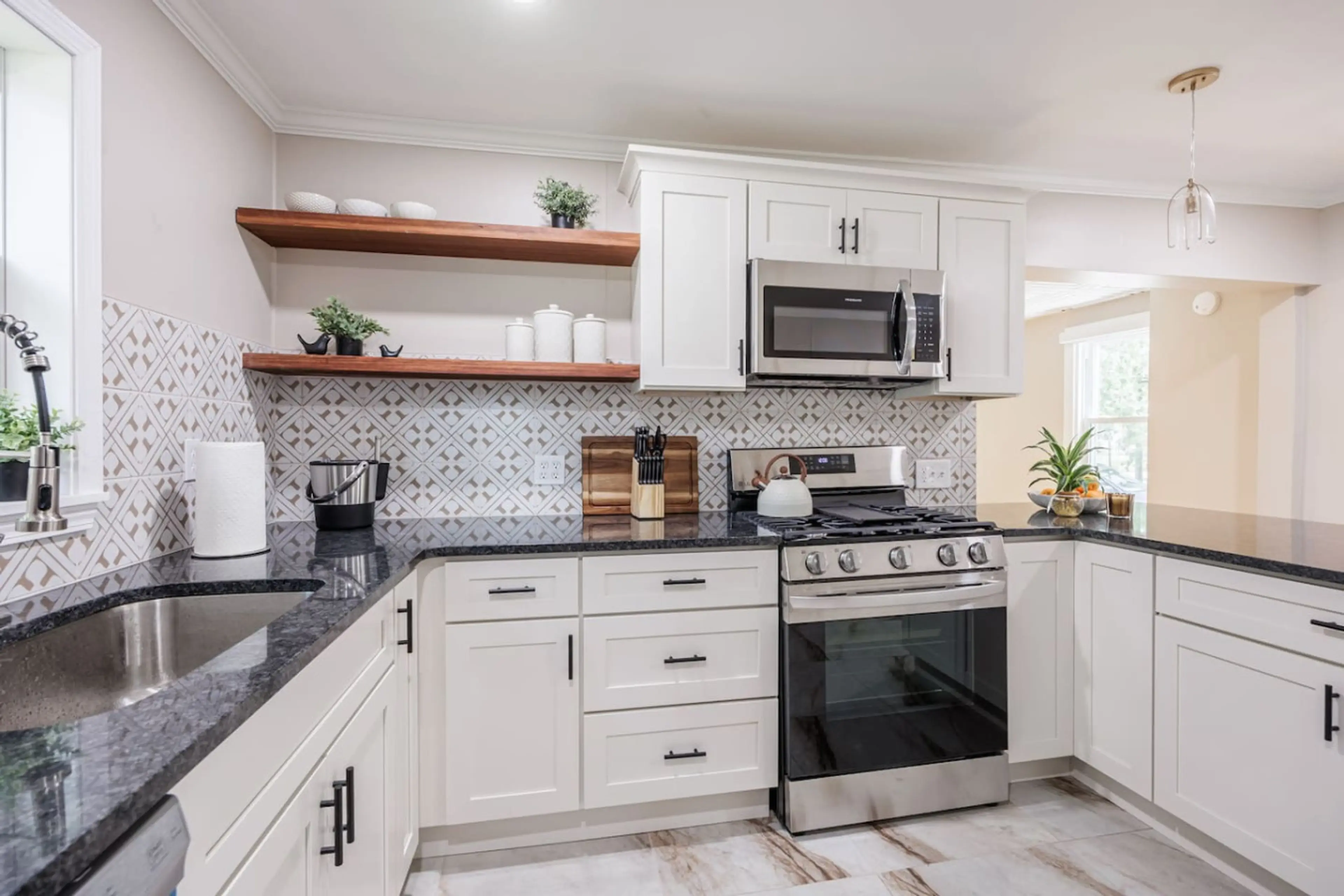 Modern gourmet kitchen featuring sleek appliances, quartz island with two stylish stools, and full cookware. A perfect blend of elegance and function for cooking or casual dining.