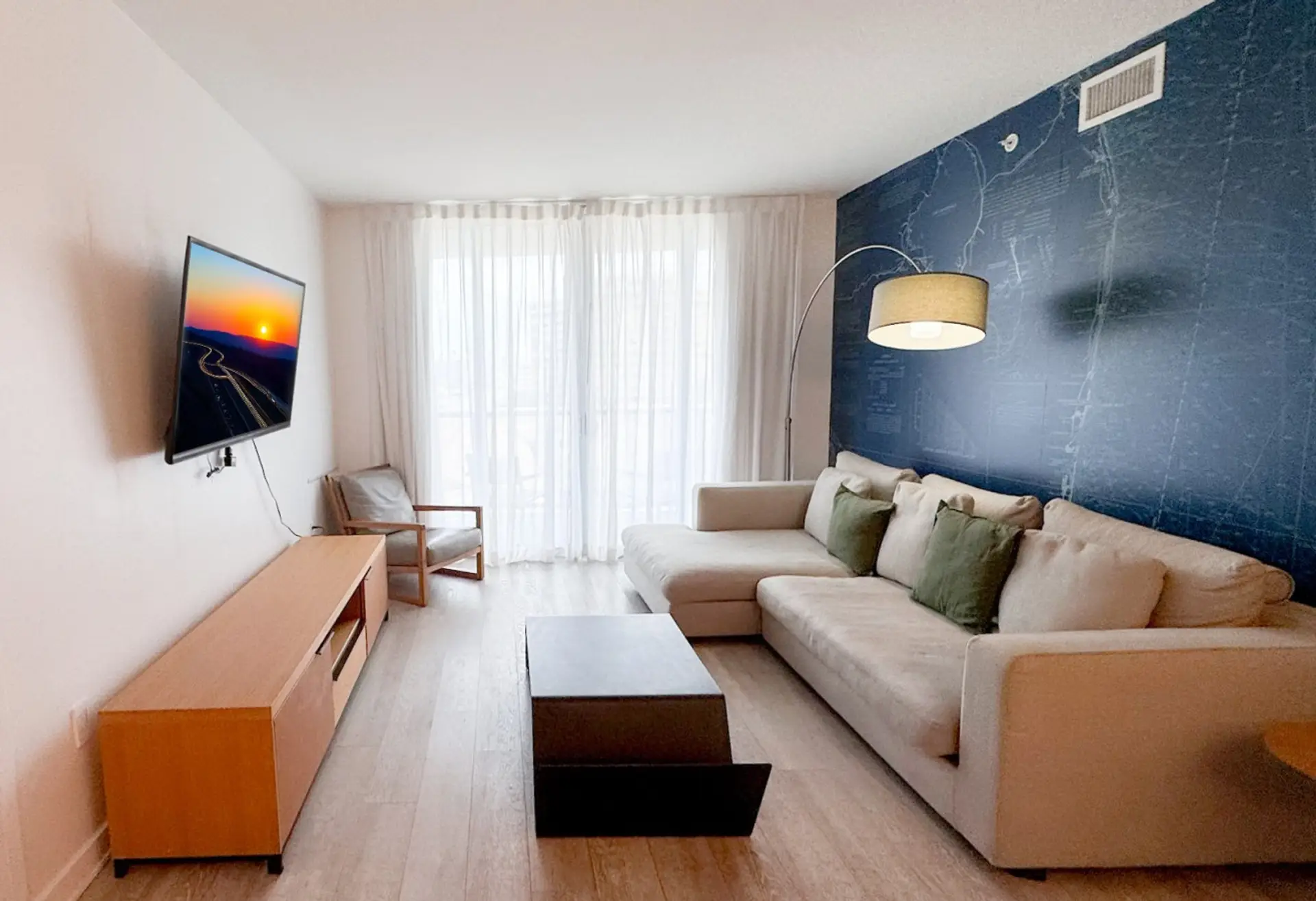Bright living room with balcony access and city views.