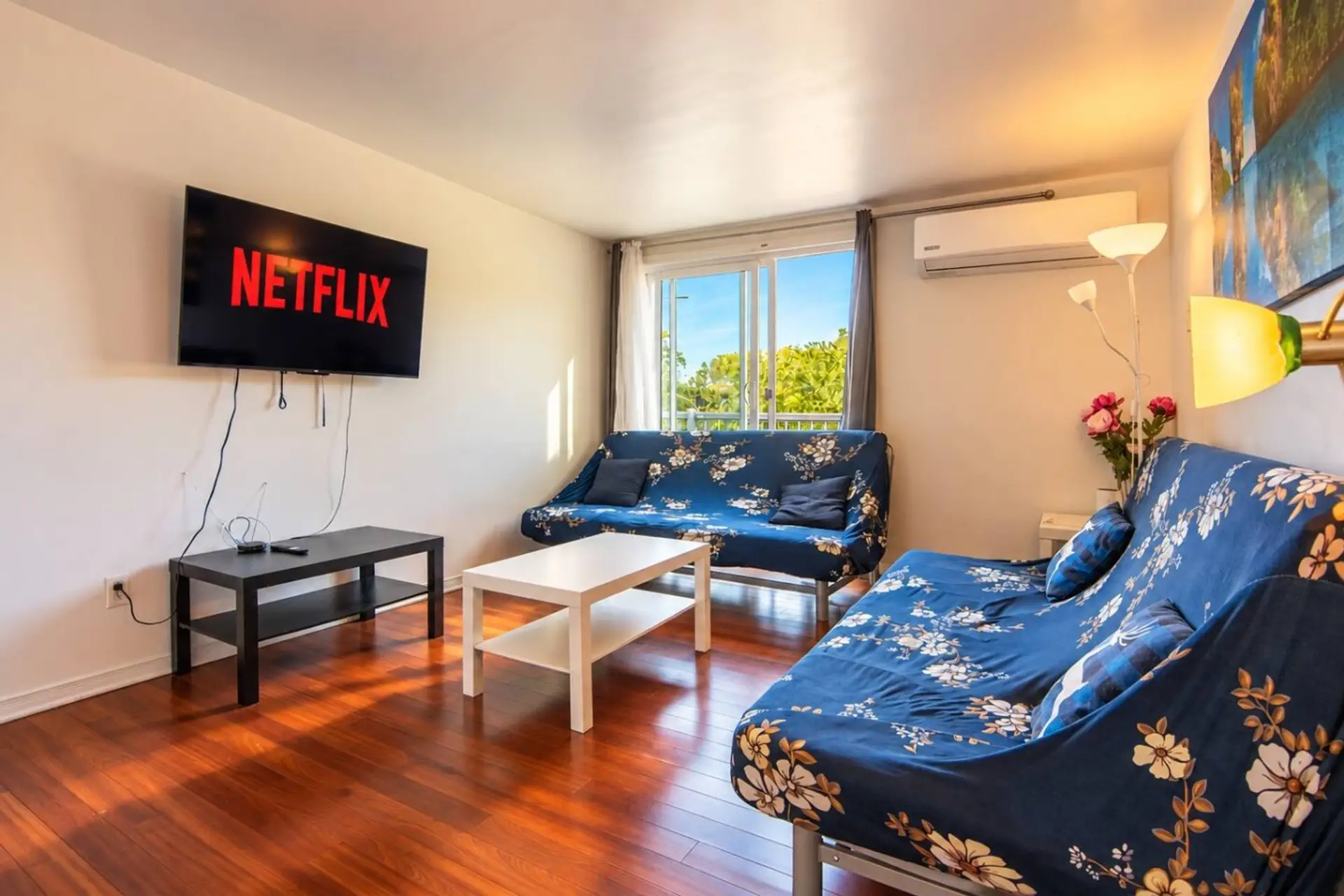 Bright lounge with two sofa beds, Smart TV and balcony access.