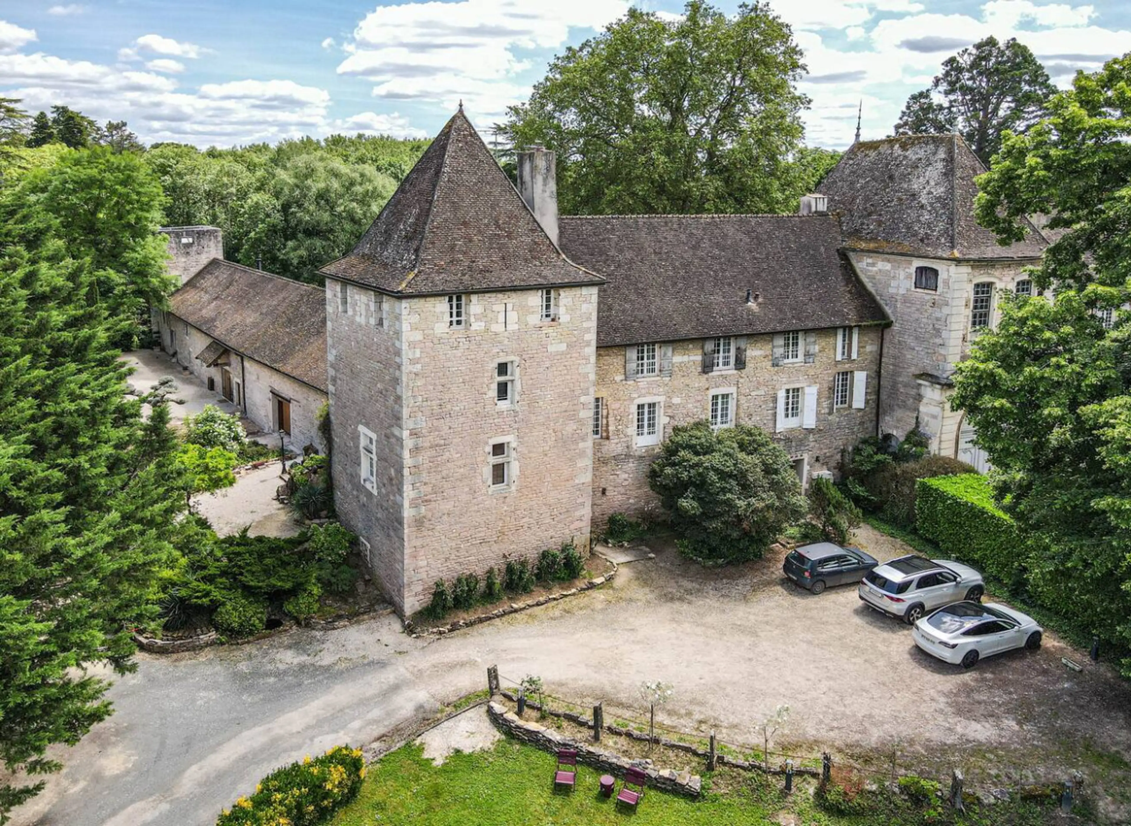 Château historique en pierre avec tours médiévales, entouré de verdure et stationnement privatif
