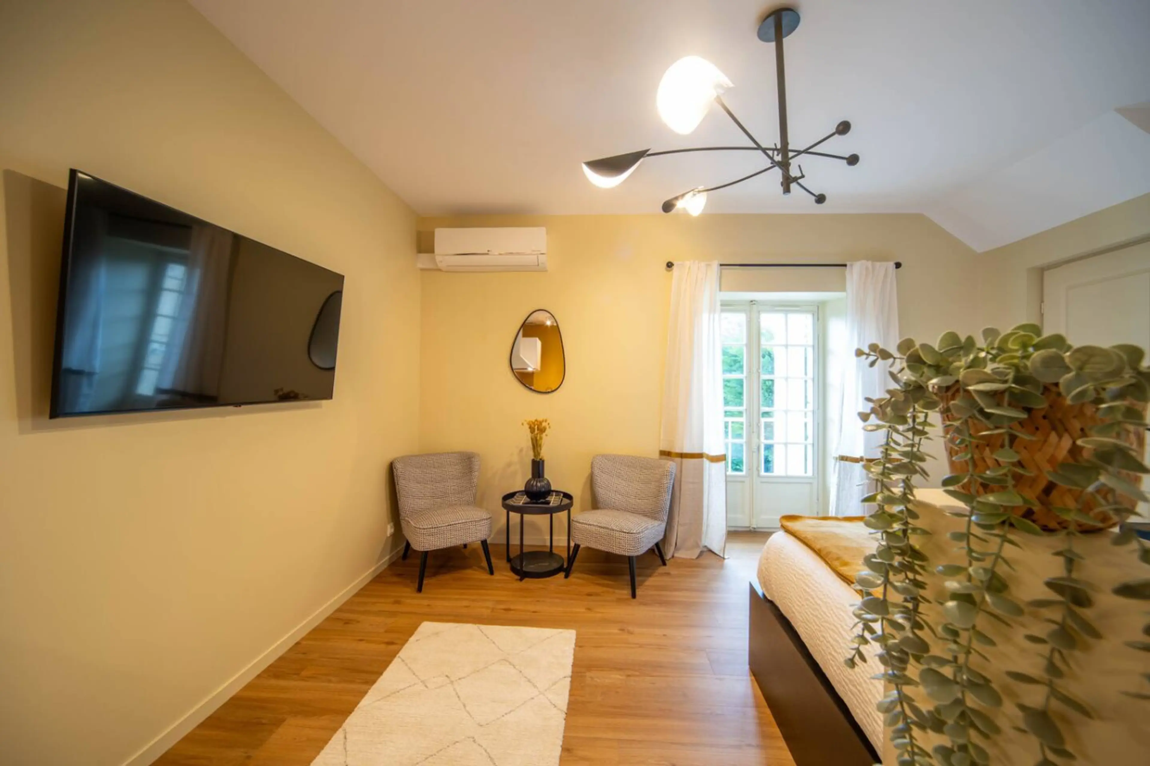Salon lumineux avec télévision murale, fauteuils confortables et accès direct à la terrasse ensoleillée