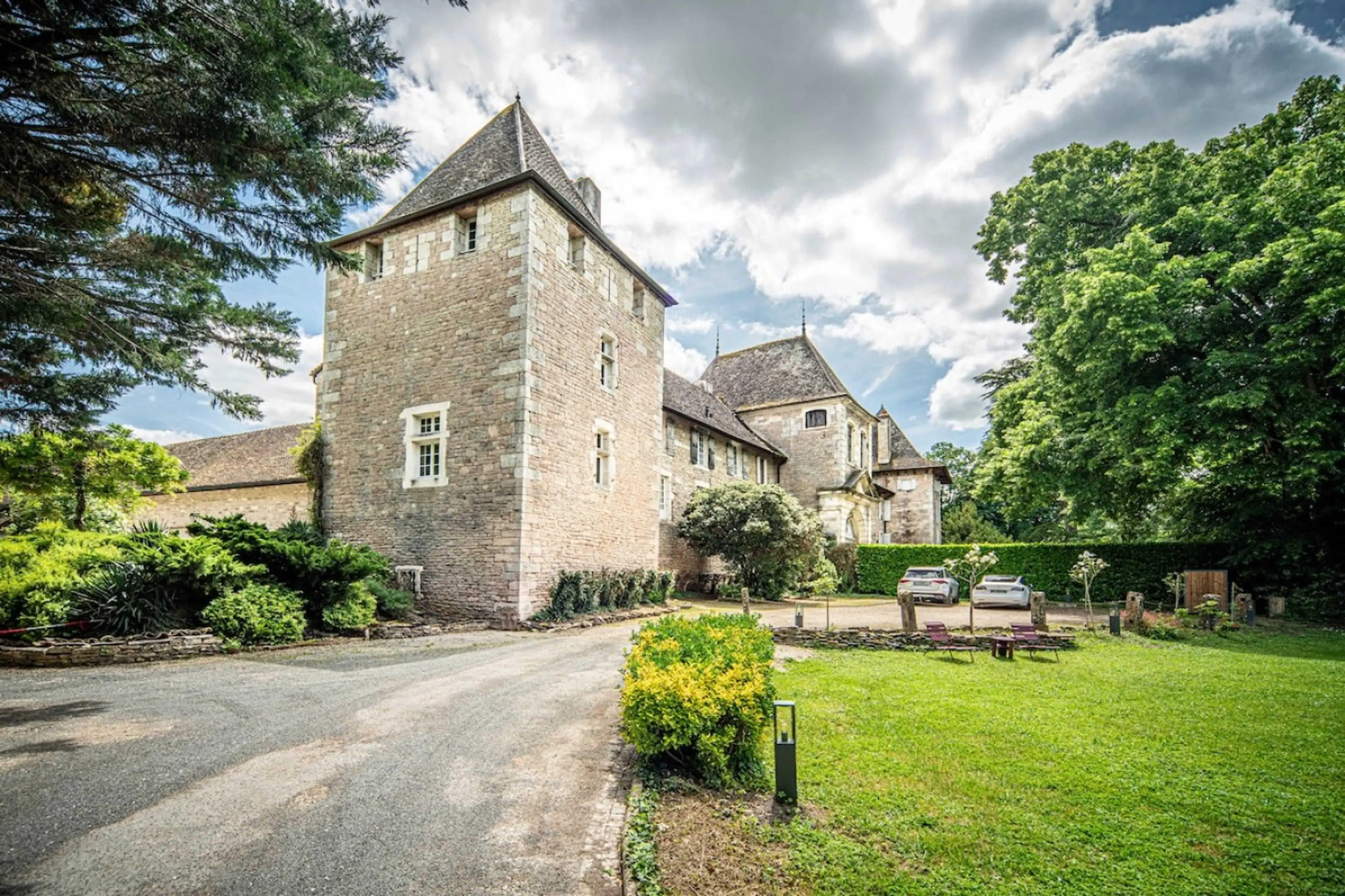 Imposant château en pierre avec tour caractéristique, entouré d'un parc verdoyant et d'espaces détente