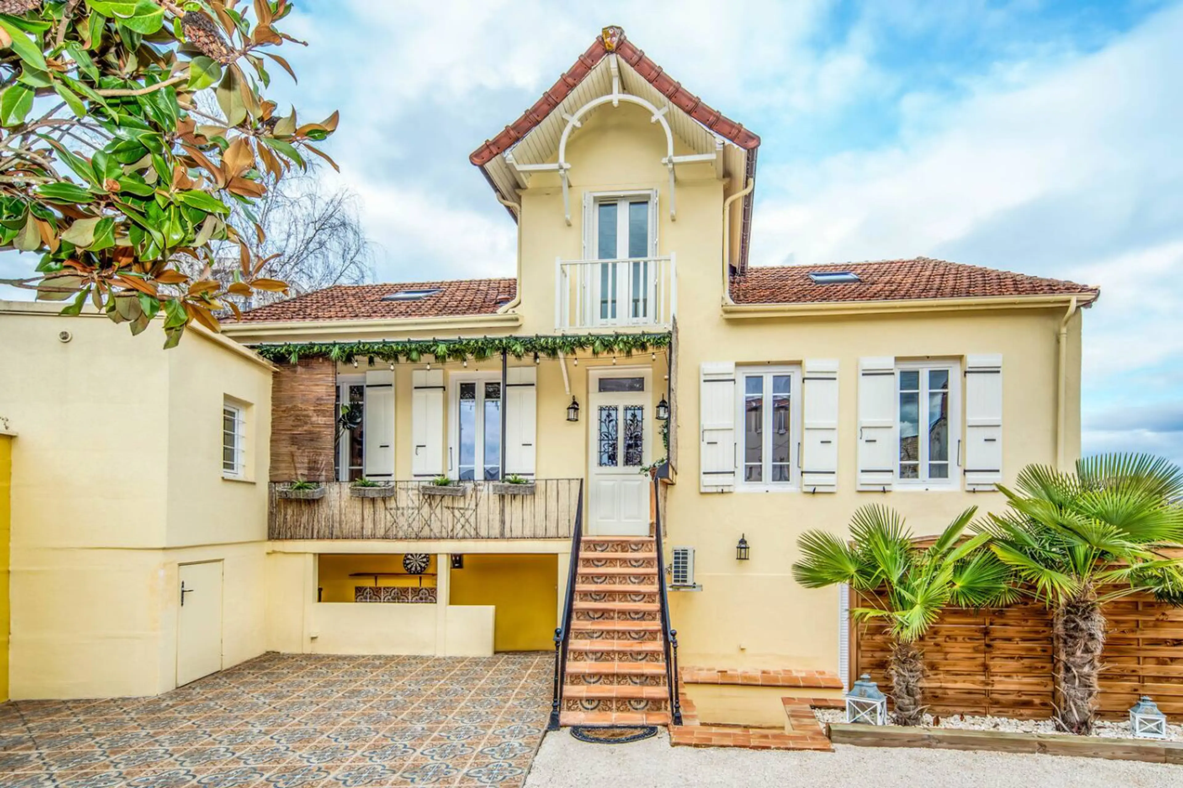 Belle demeure de charme avec façade jaune pastel, escalier extérieur et terrasse aménagée