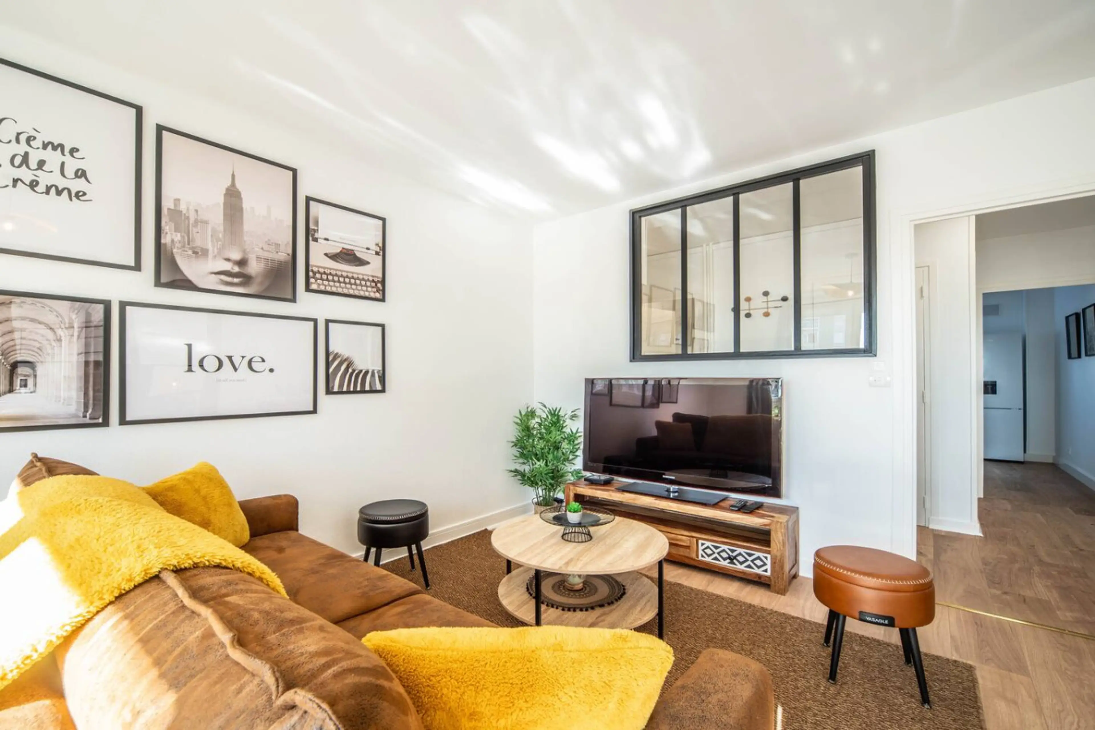 Salon confortable avec canapé marron, coussins jaunes, télévision et décoration murale inspirante