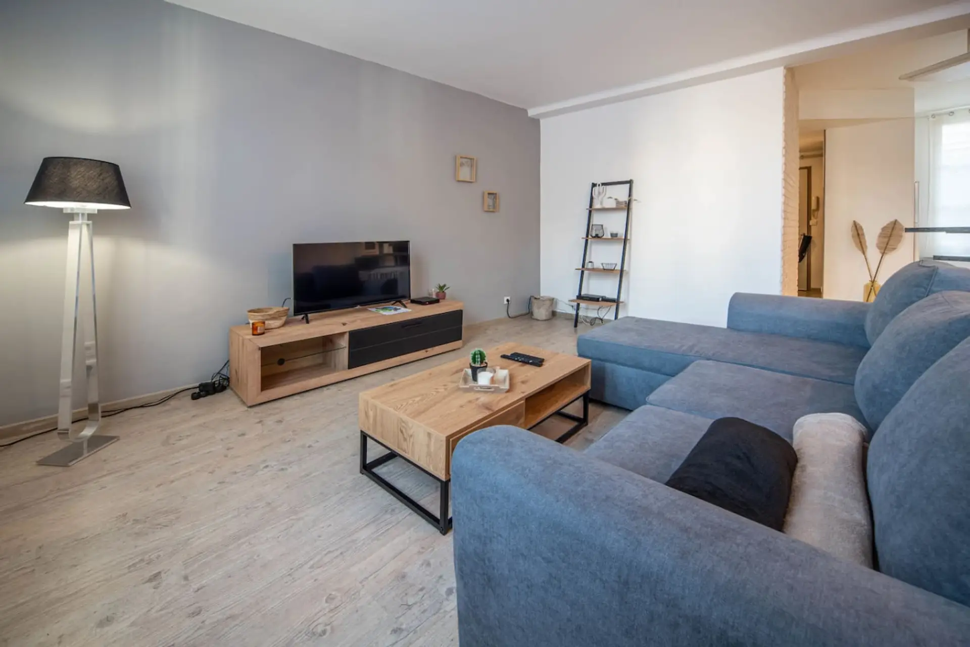 Salon lumineux et spacieux avec canapés bleus confortables, téléviseur et mobilier bois naturel