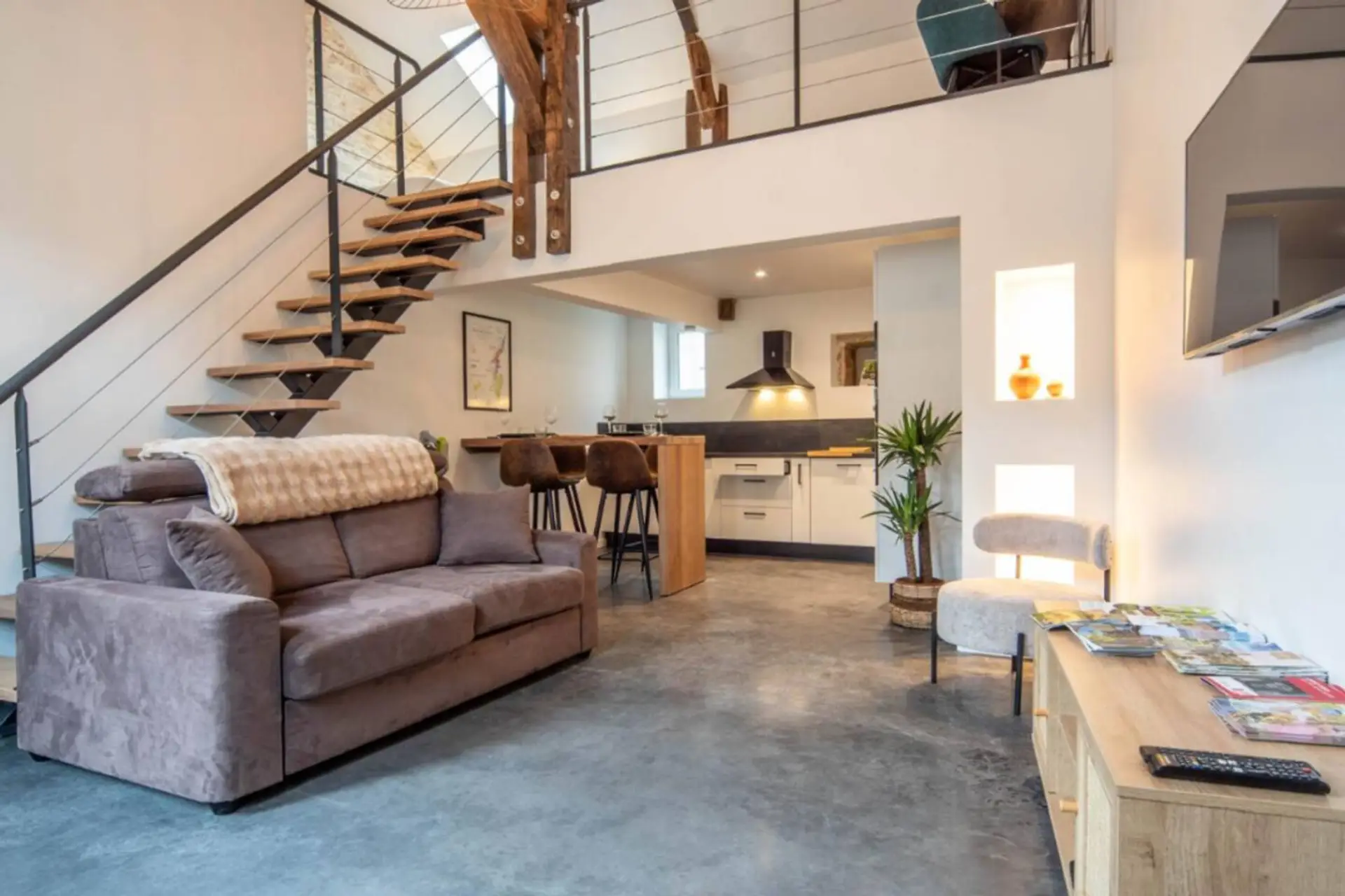 Spacieux loft lumineux avec salon confortable, cuisine ouverte équipée et escalier en bois vers mezzanine