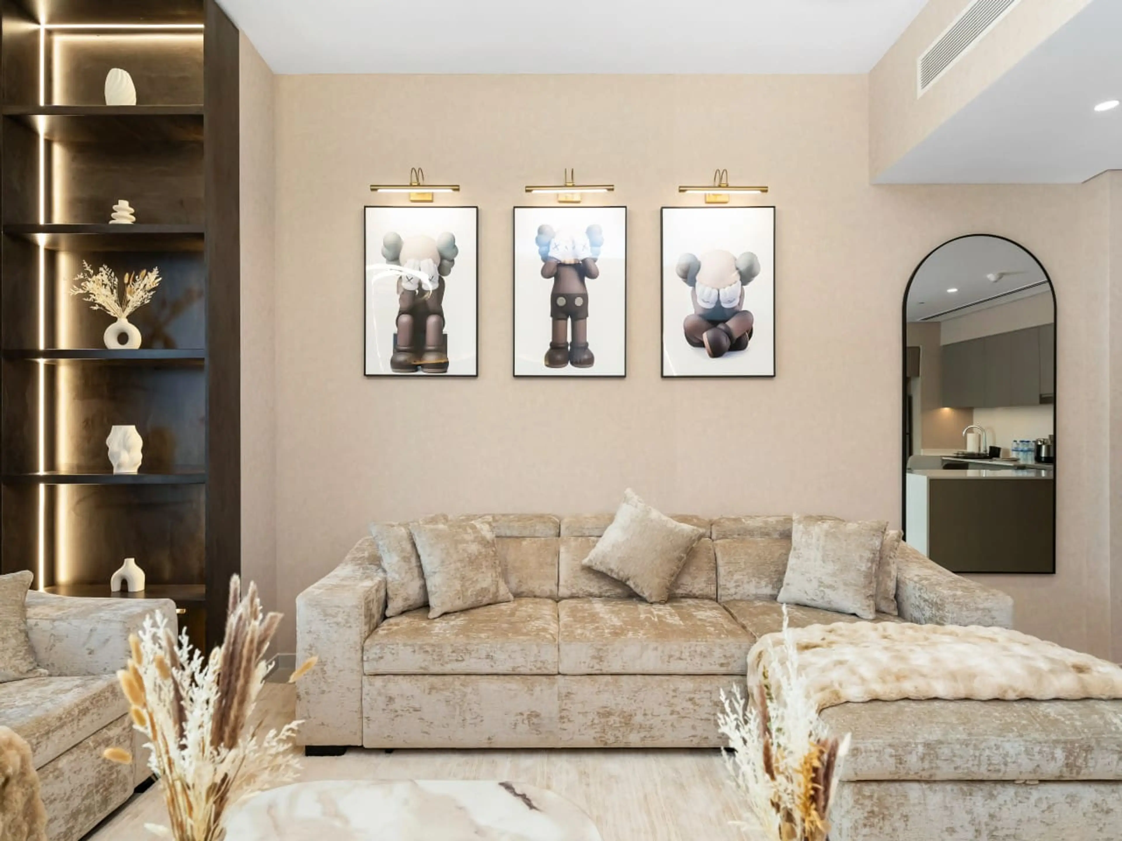 Spacious living room featuring a comfortable sofa bed, modern design elements, and distinctive Bearbricks artwork. This stylish Downtown Dubai vacation home offers a perfect blend of contemporary comfort and artistic charm.