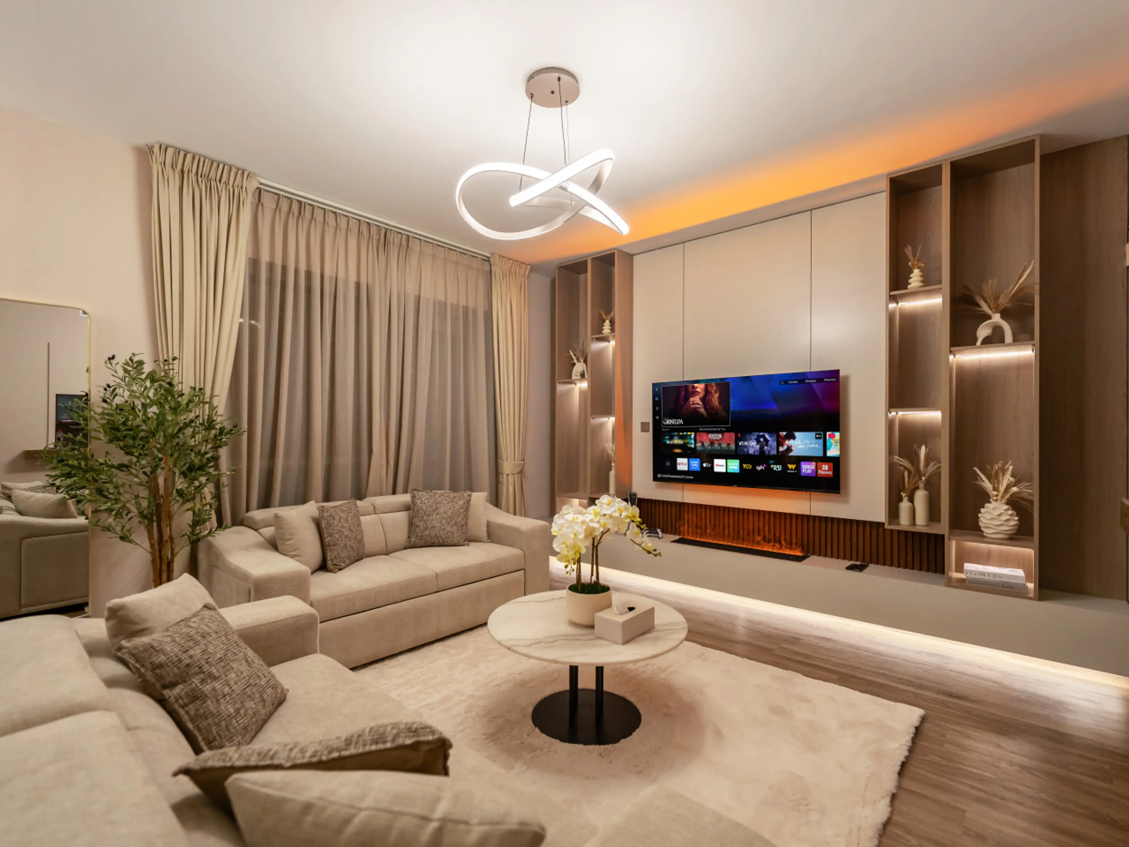 Modern luxury living room with ambient LED lighting, smart TV, plush sectional sofa, and elegant built-ins — the perfect space to relax after a day exploring.