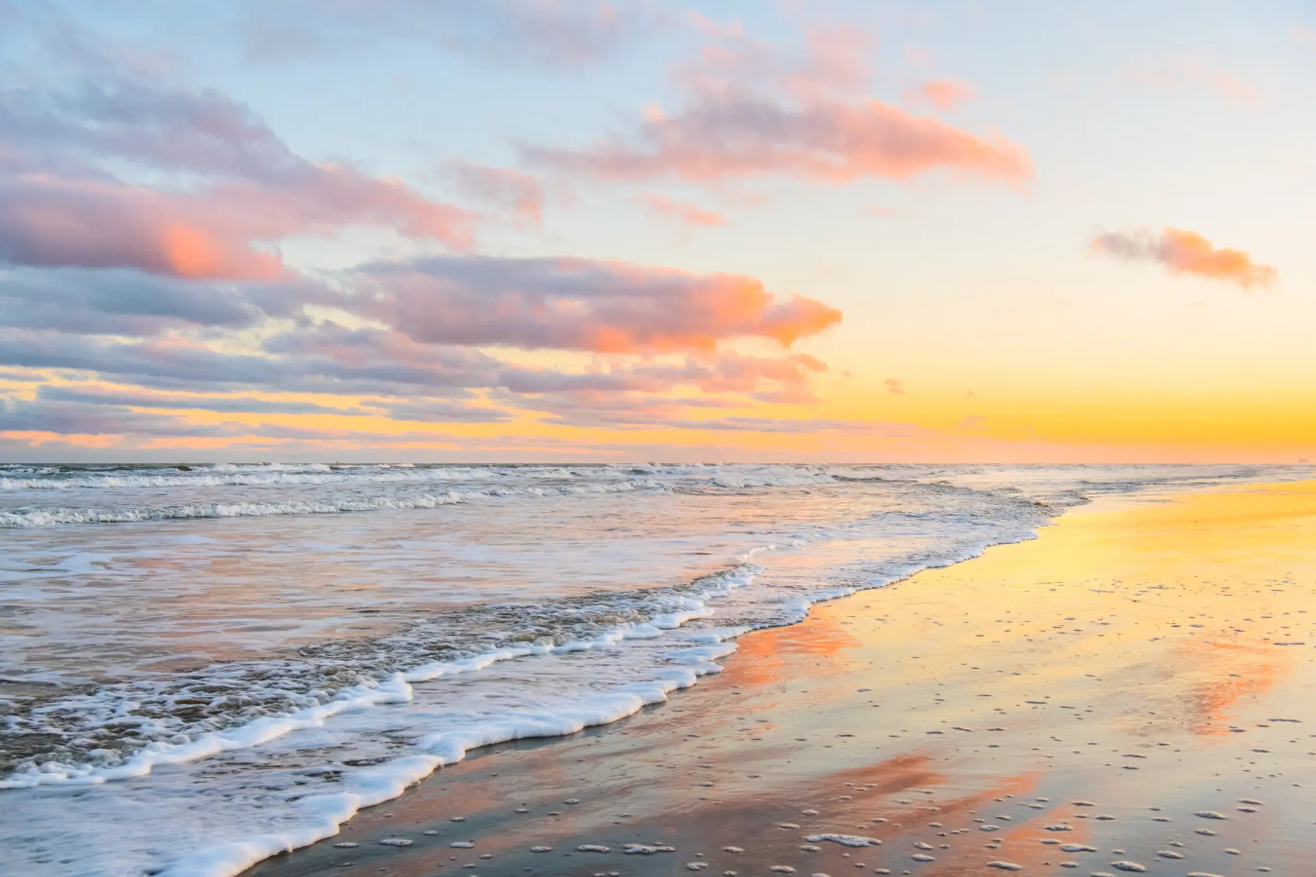 Golden sunrise over rolling waves—wake up to serene beachfront views just steps from your stay