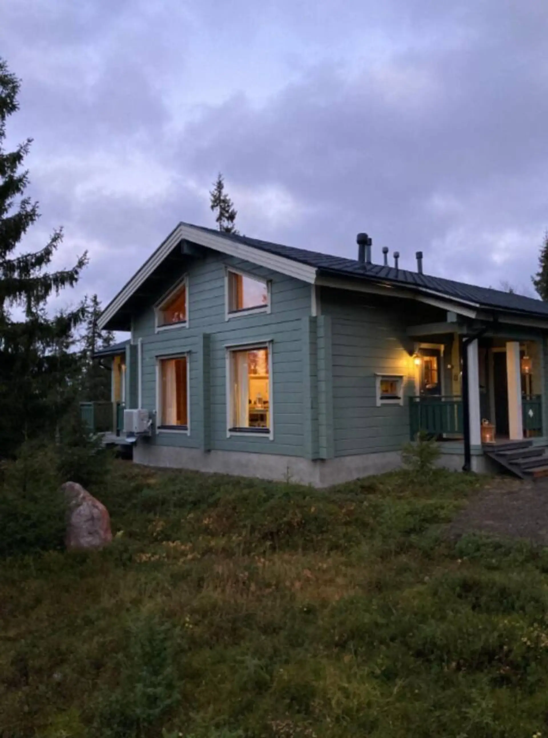 Log-built exterior of the apartment with warmly lit windows in the evening.