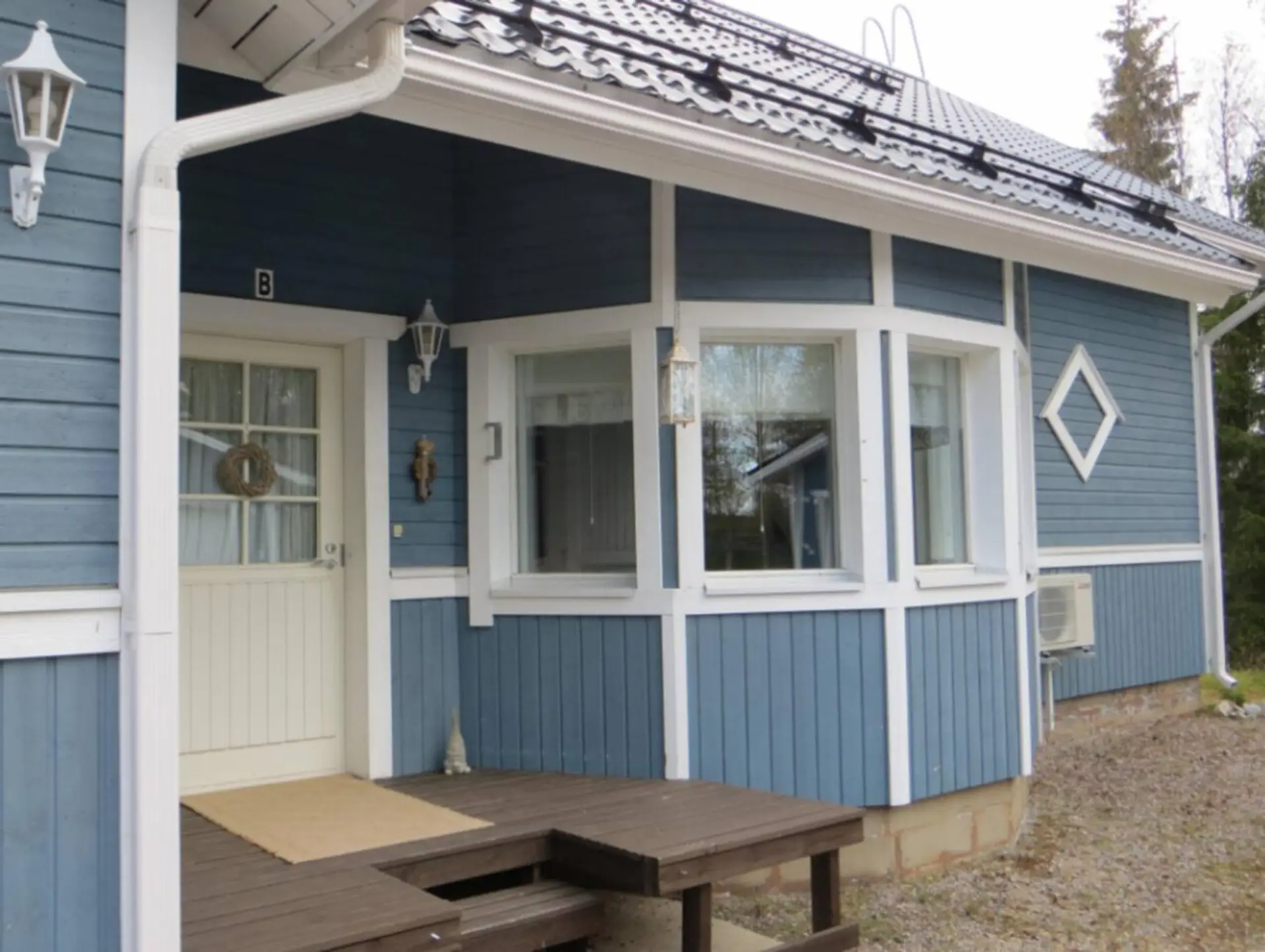 Exterior view of the blue semi-detached apartment with its own covered entrance.