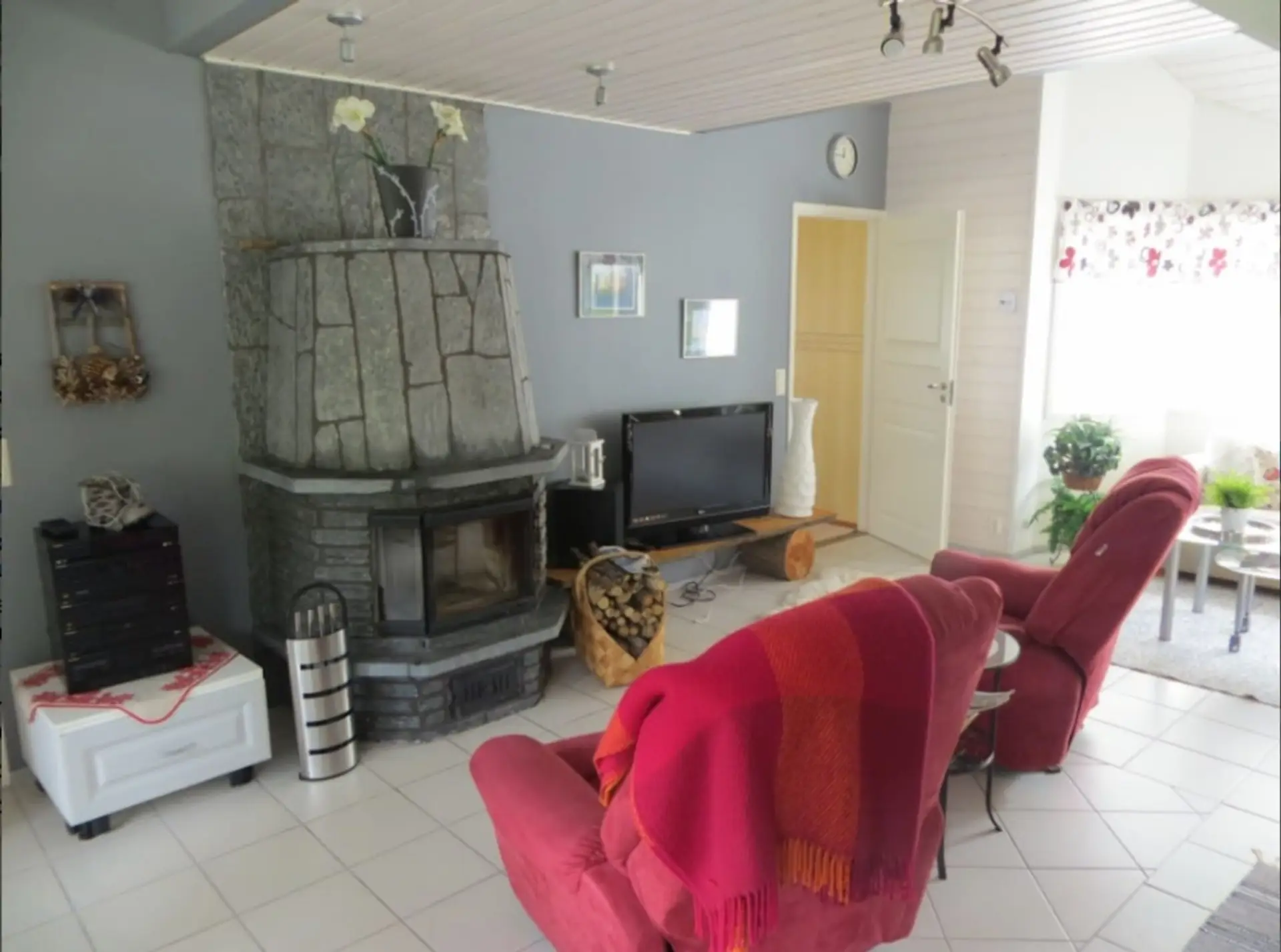 Living room with a stone fireplace, flat-screen TV and reclining armchairs.