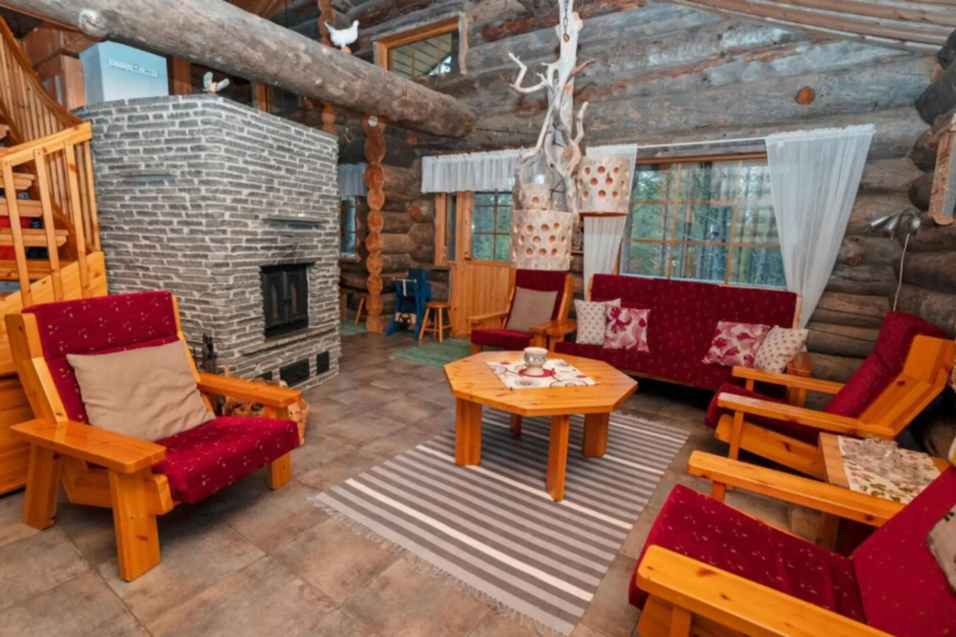 Spacious living room with a stone fireplace and comfortable armchairs around a coffee table.