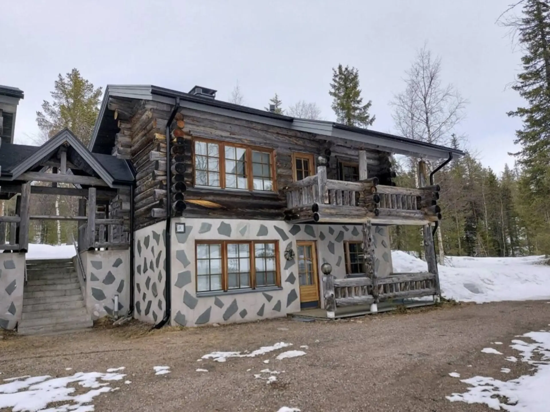 Exterior view of the kelo log building with balconies and a snow-covered yard.
