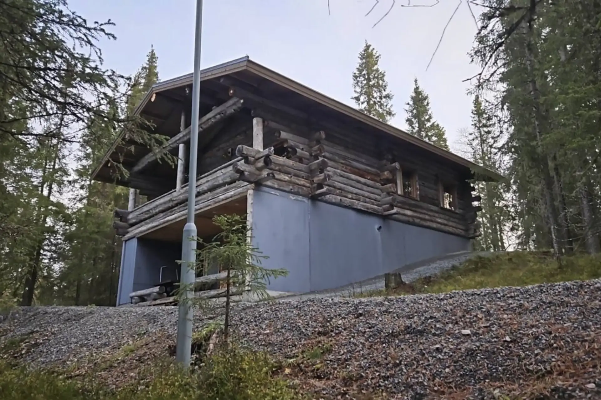 Exterior view of the two-storey log cabin surrounded by spruce forest.