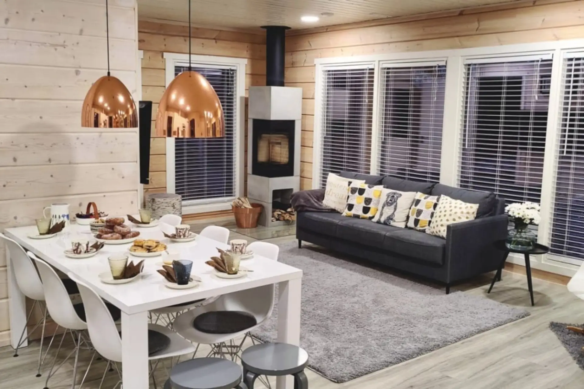 Open-plan living and dining area with a fireplace, a large dining table and a comfortable sofa.