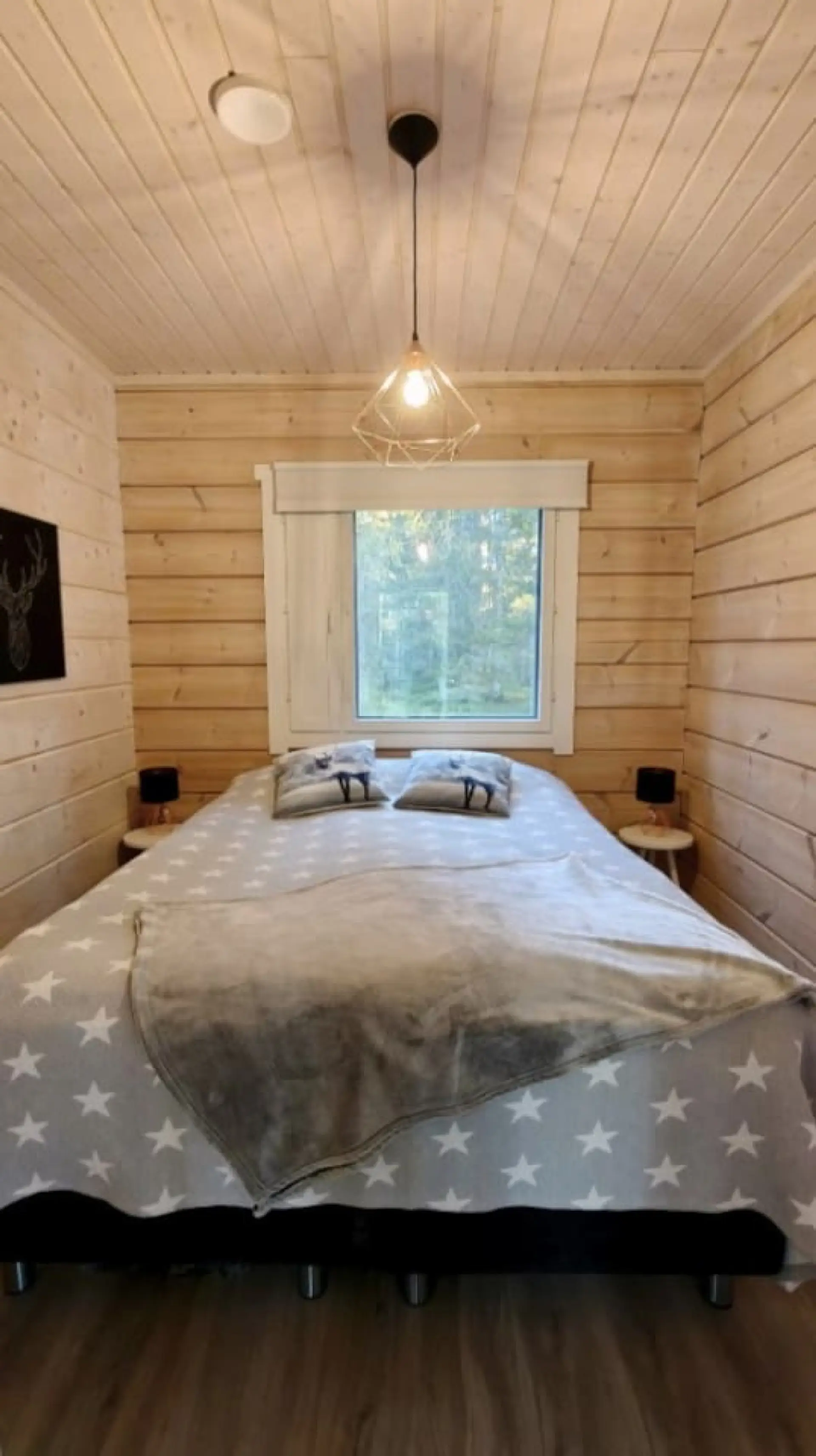 Bedroom with a double bed, bedside tables and a forest view.