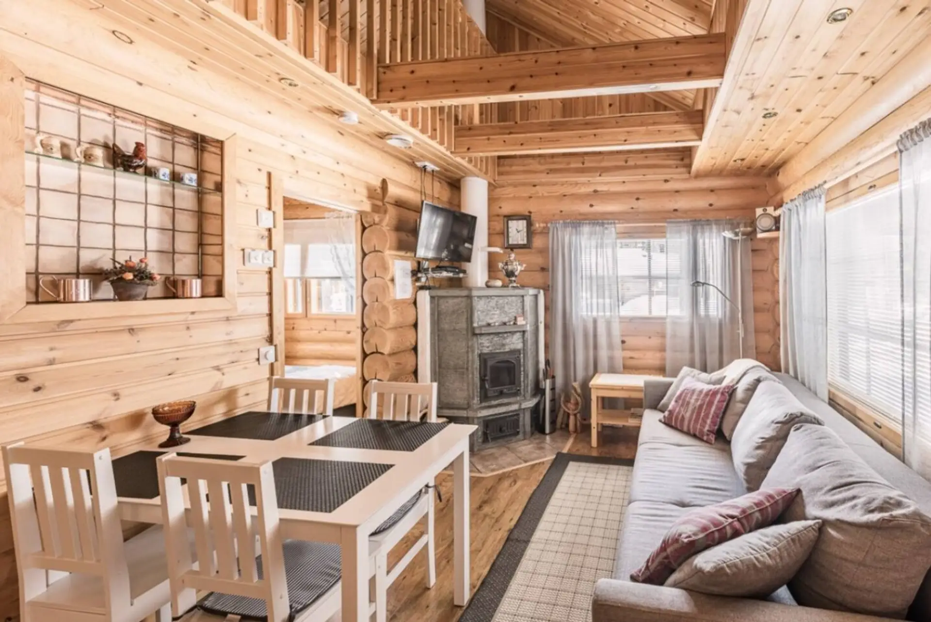 Bright open-plan living room and kitchen area with a wood-burning fireplace, a dining table, and a comfortable sofa.