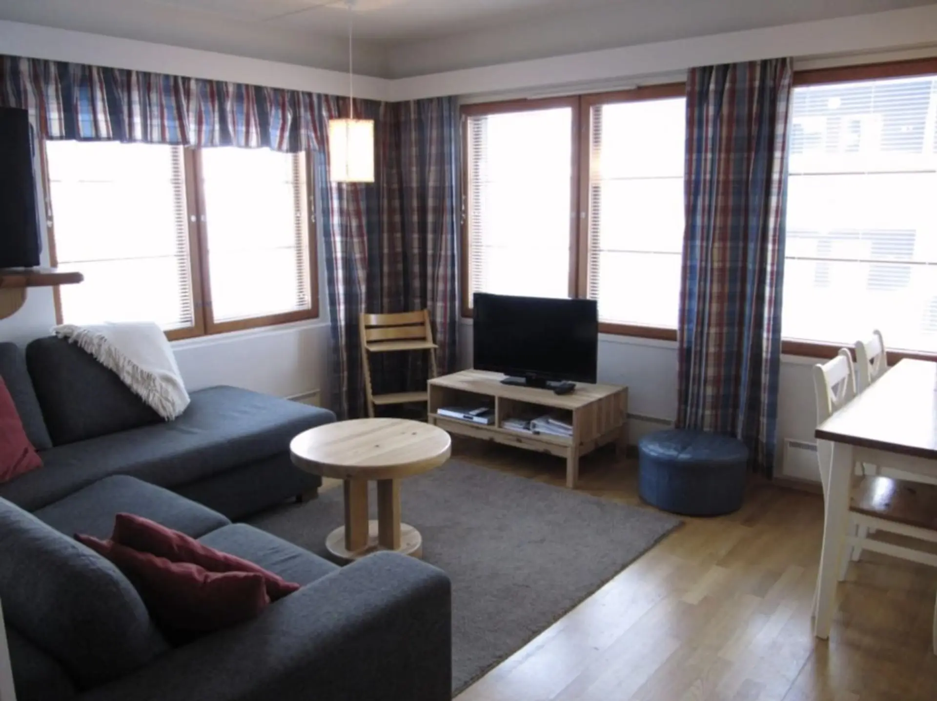 Living room with a comfortable sofa, coffee table and TV beside large windows.