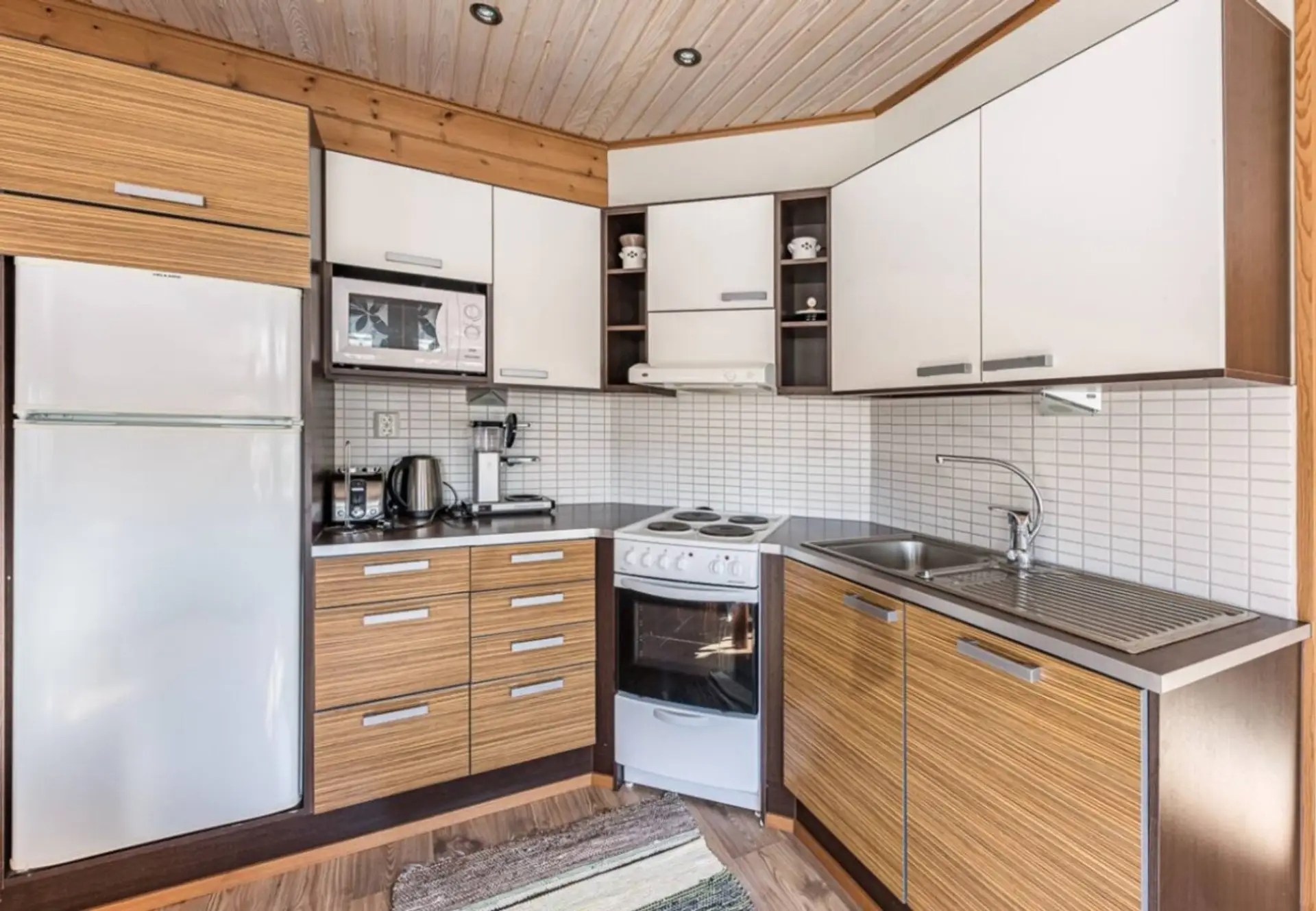 Fully equipped kitchen with an electric stove and oven, fridge-freezer, microwave, coffee maker and kettle.