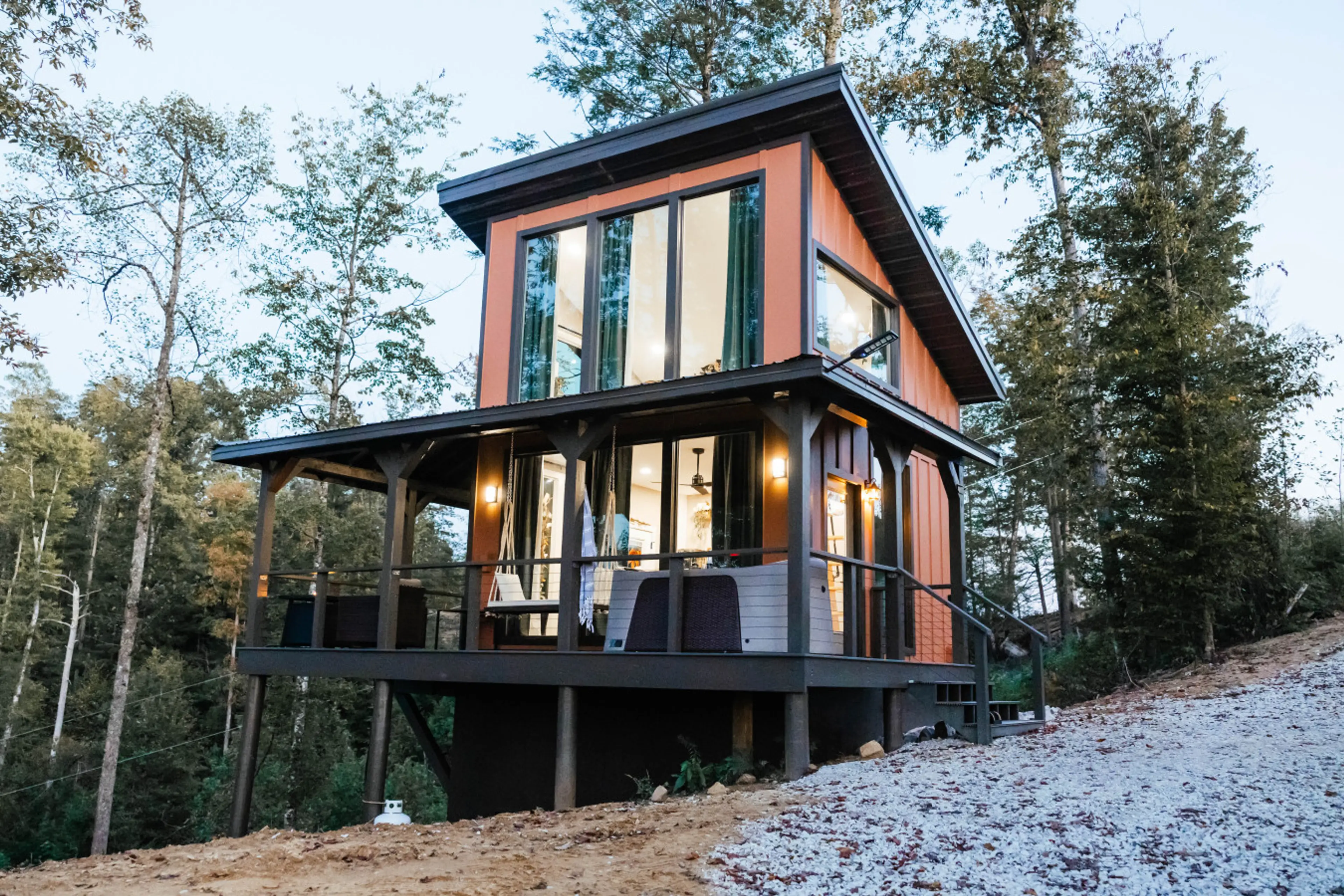 Modern cabin exterior nestled in the woods with a private wraparound deck and large scenic windows.