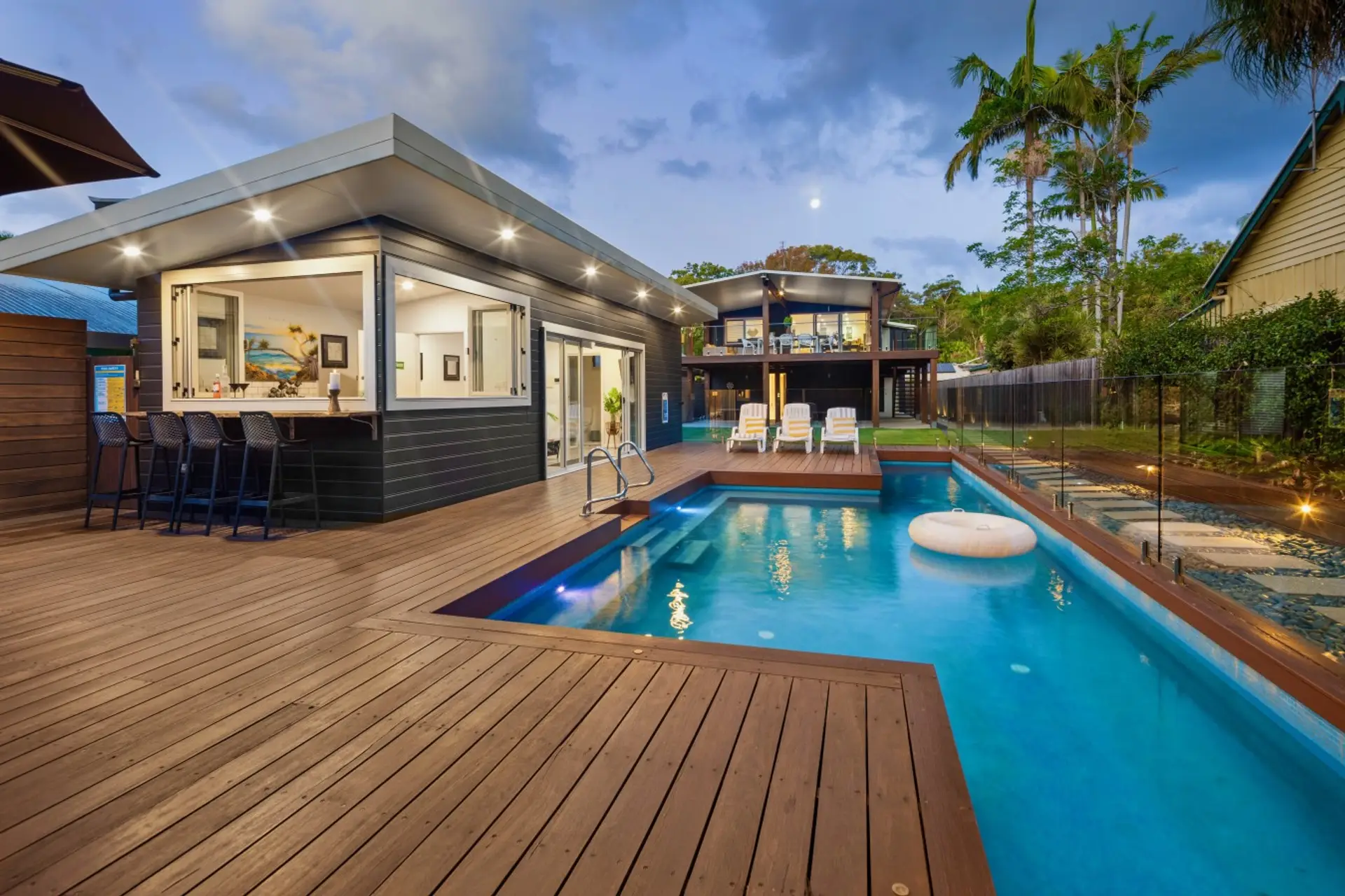 Heated pool, pool house bar and upper entertaining deck lit at dusk — the full Perrins Lane Compound experience, South West Rocks