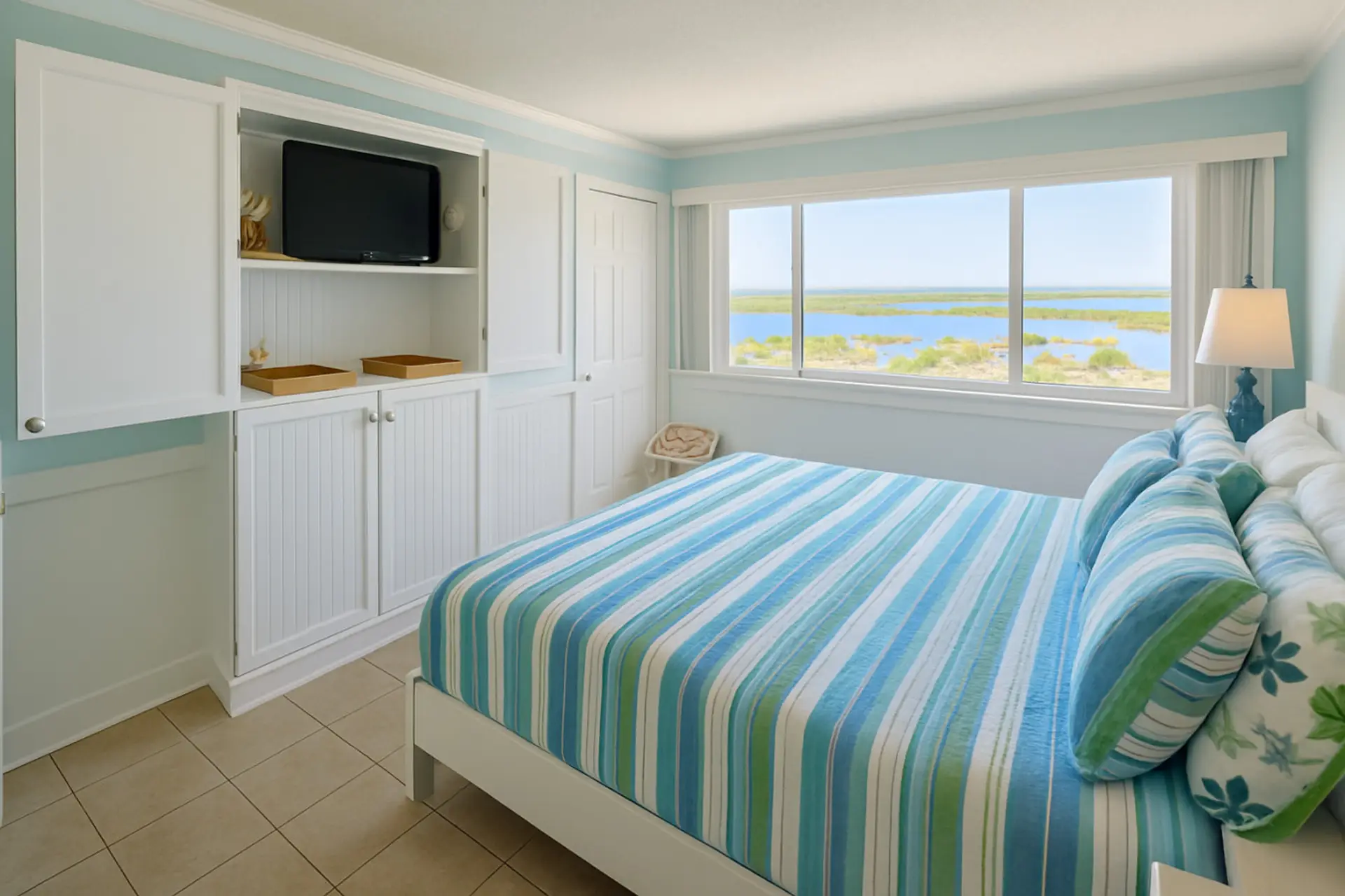 Sunlit bedroom with bay views and coastal bedding