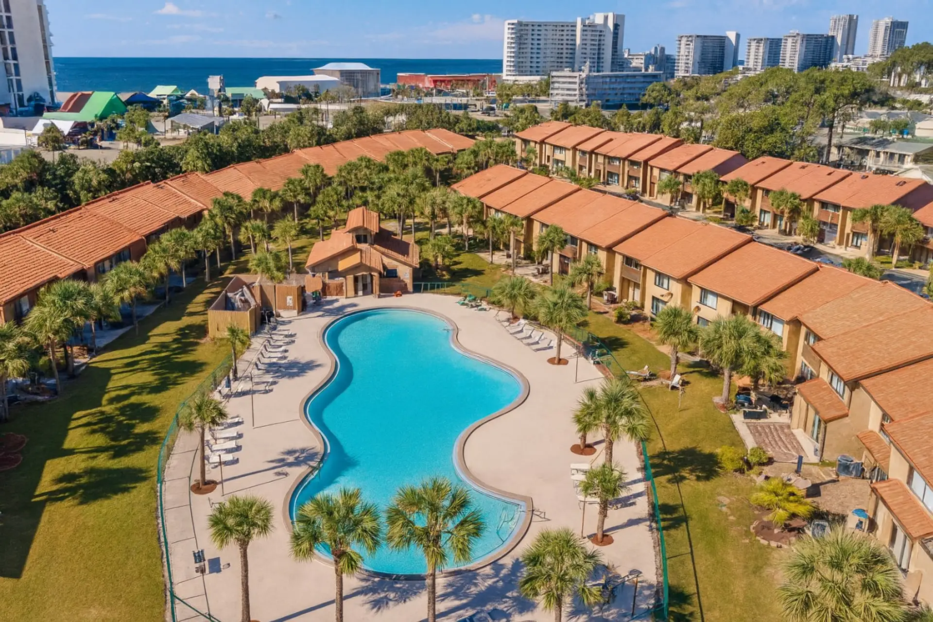 Kidney-shaped community pool amid palm-lined townhomes
