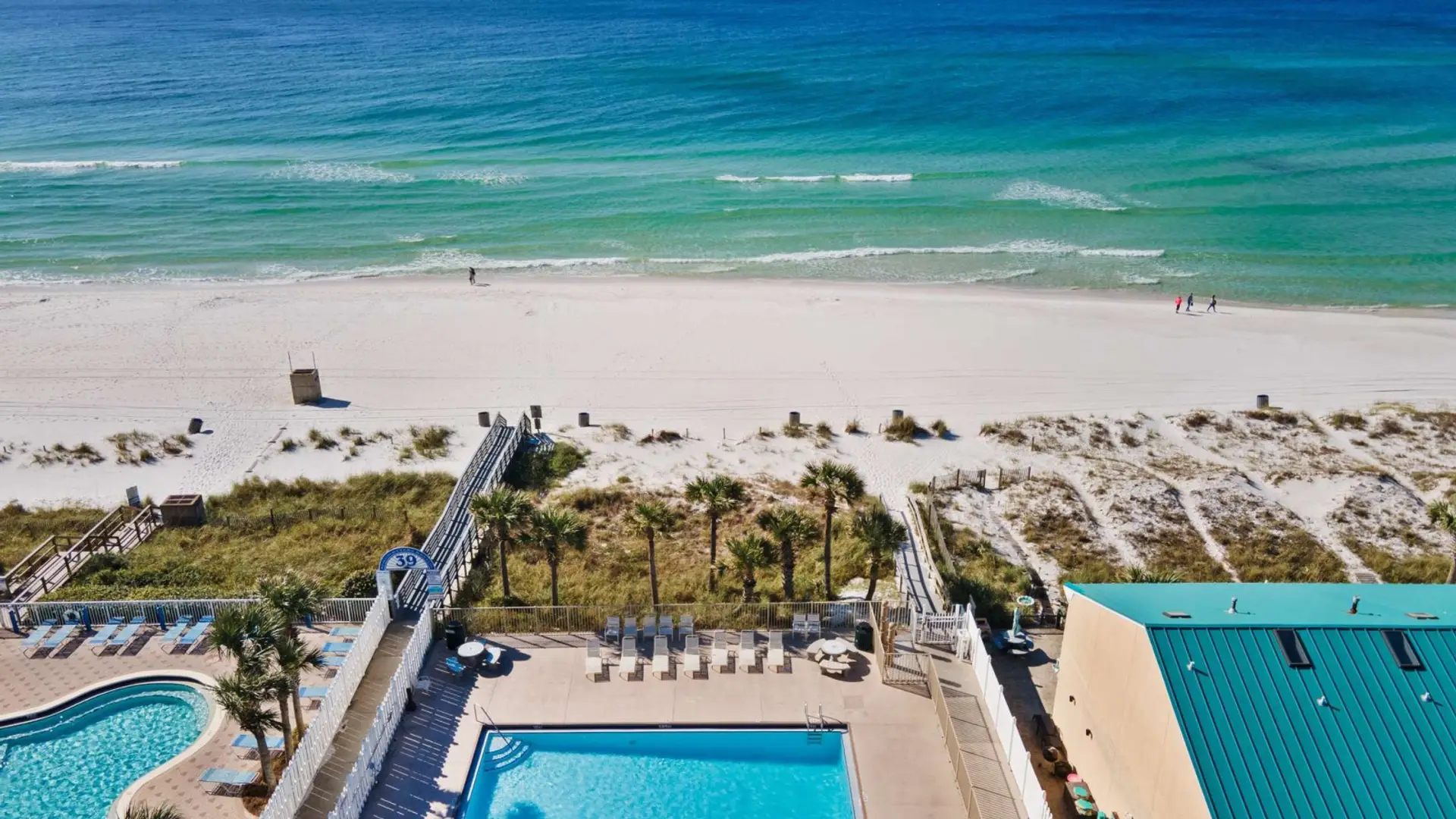 Pool deck and boardwalk leading to white sand beach