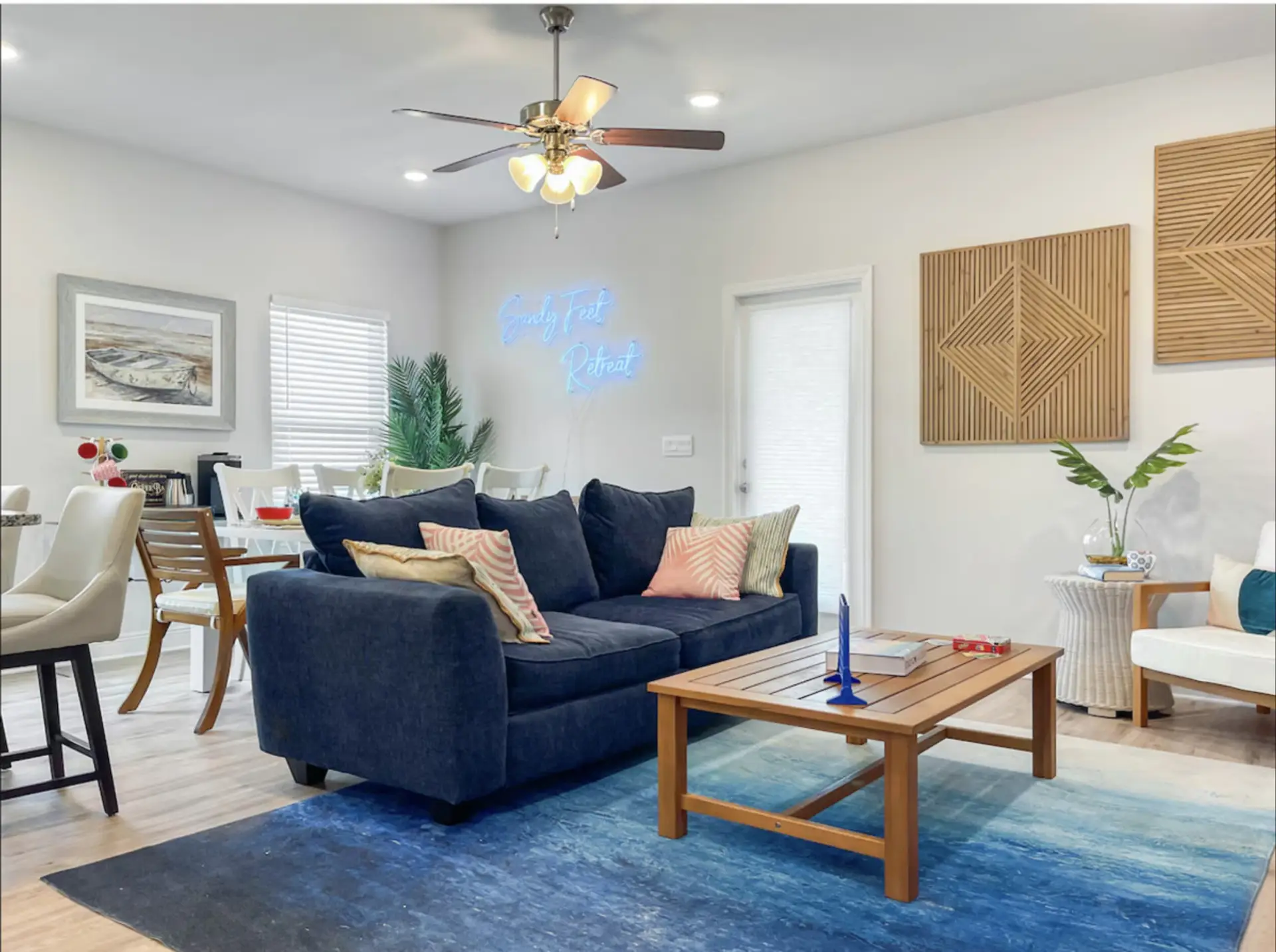Navy sofa under glowing Sandy Feet Retreat neon