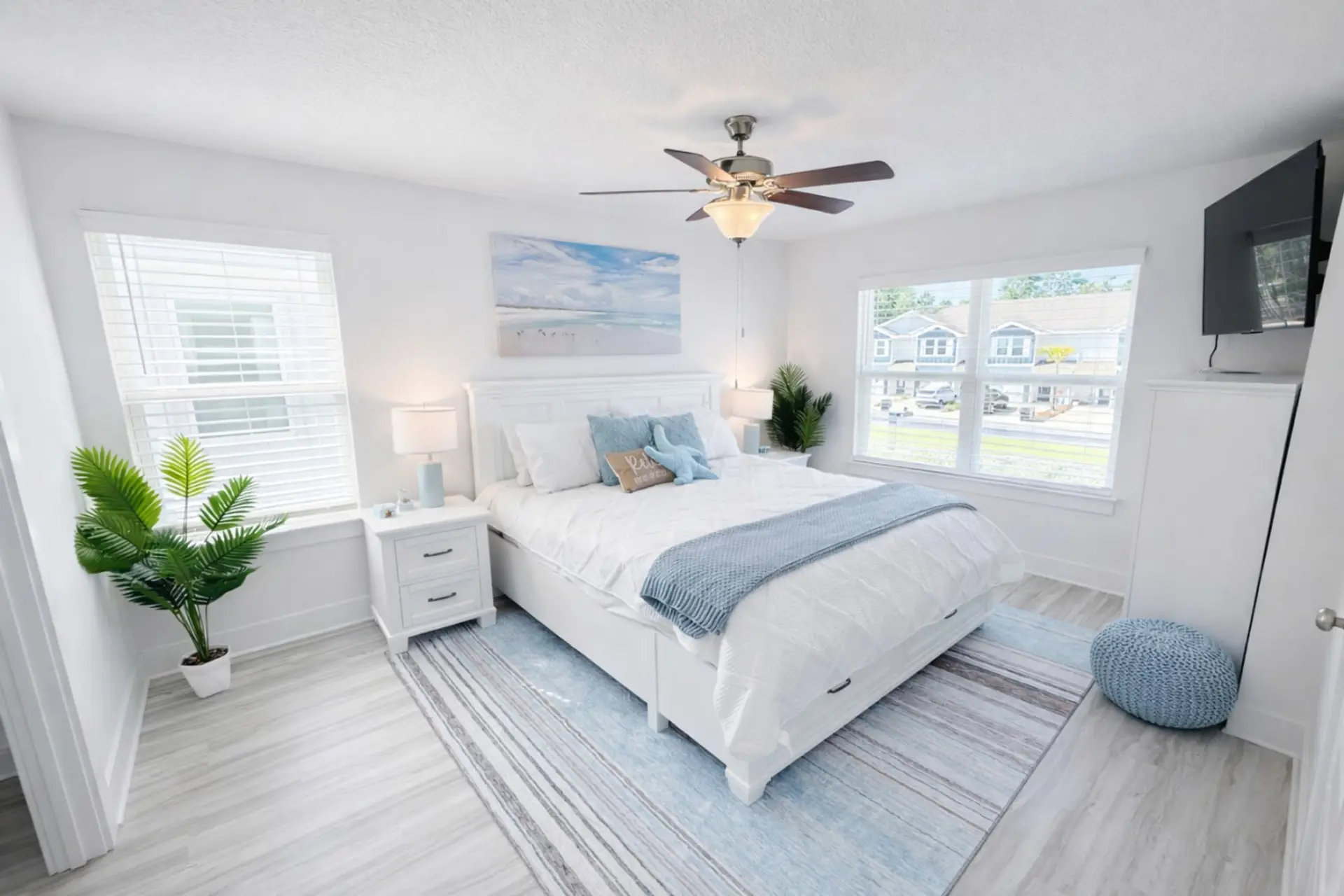 Bright and airy primary suite featuring a comfortable king bed, coastal décor, and plenty of natural light