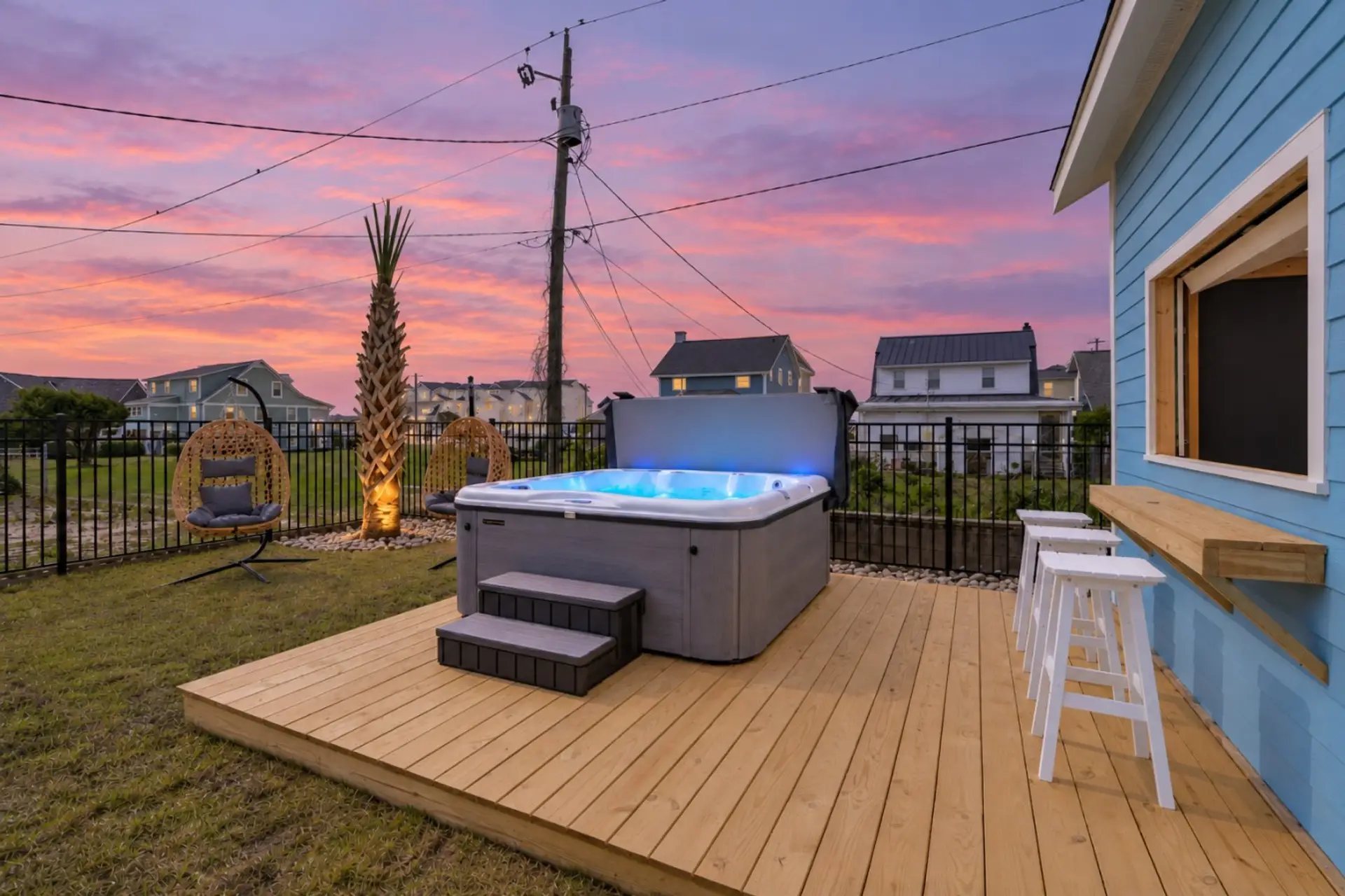 The backyard after the beach: a hot tub on a new wood deck, two hanging egg chairs, and nowhere you need to be.