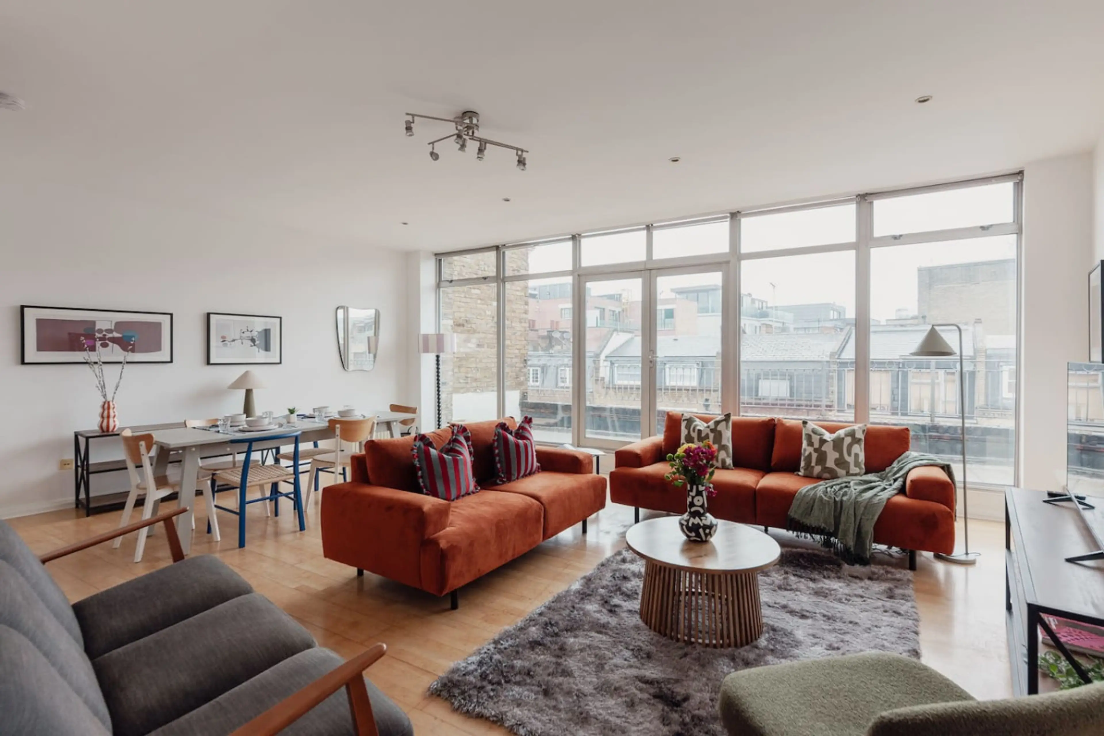 The seating area has two stylish burnt-orange sofas with patterned cushions.