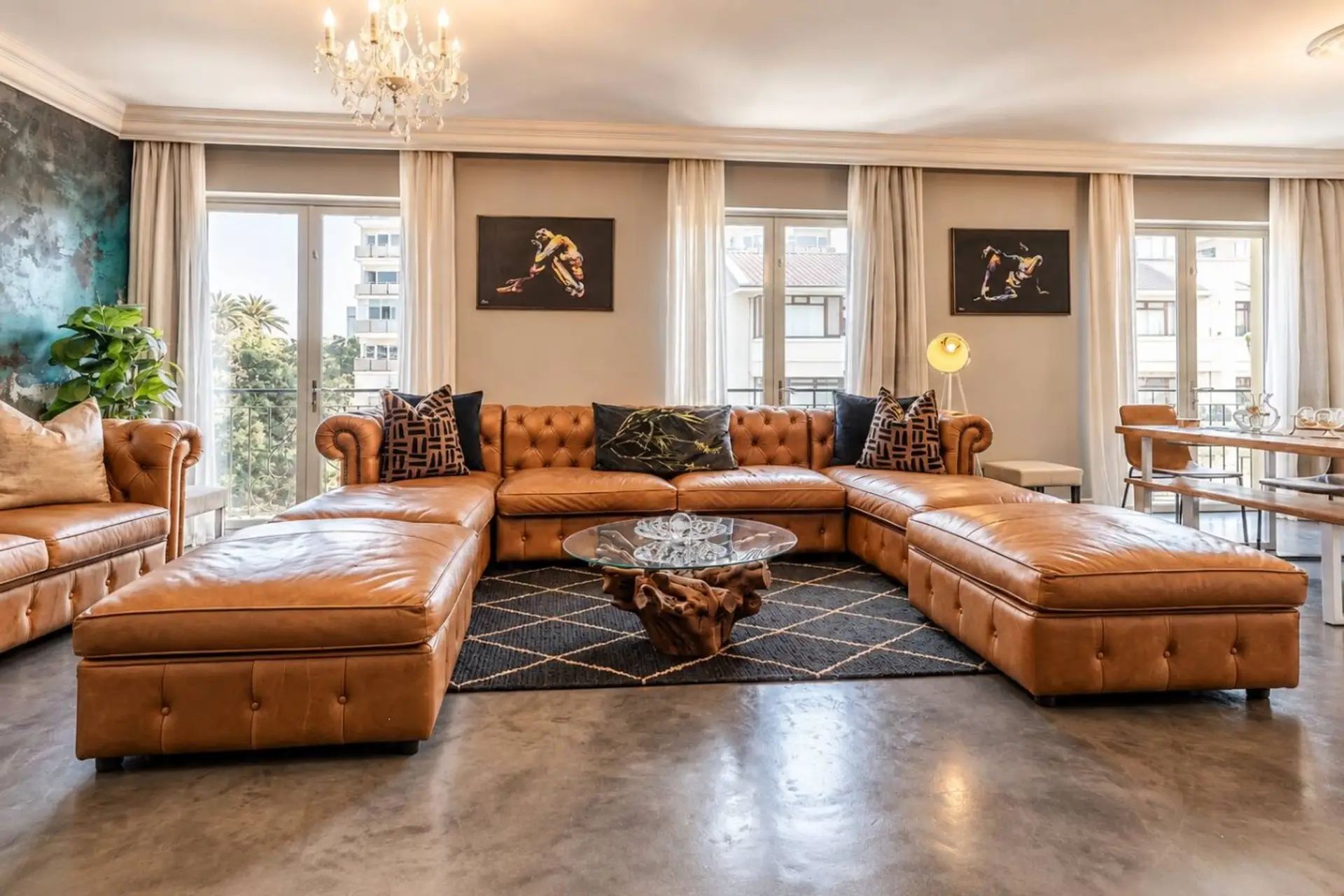Statement Lounge: Sink into the expansive caramel leather sectional, framed by artistic accents, a sparkling chandelier and generous windows that fill the room with natural light.
