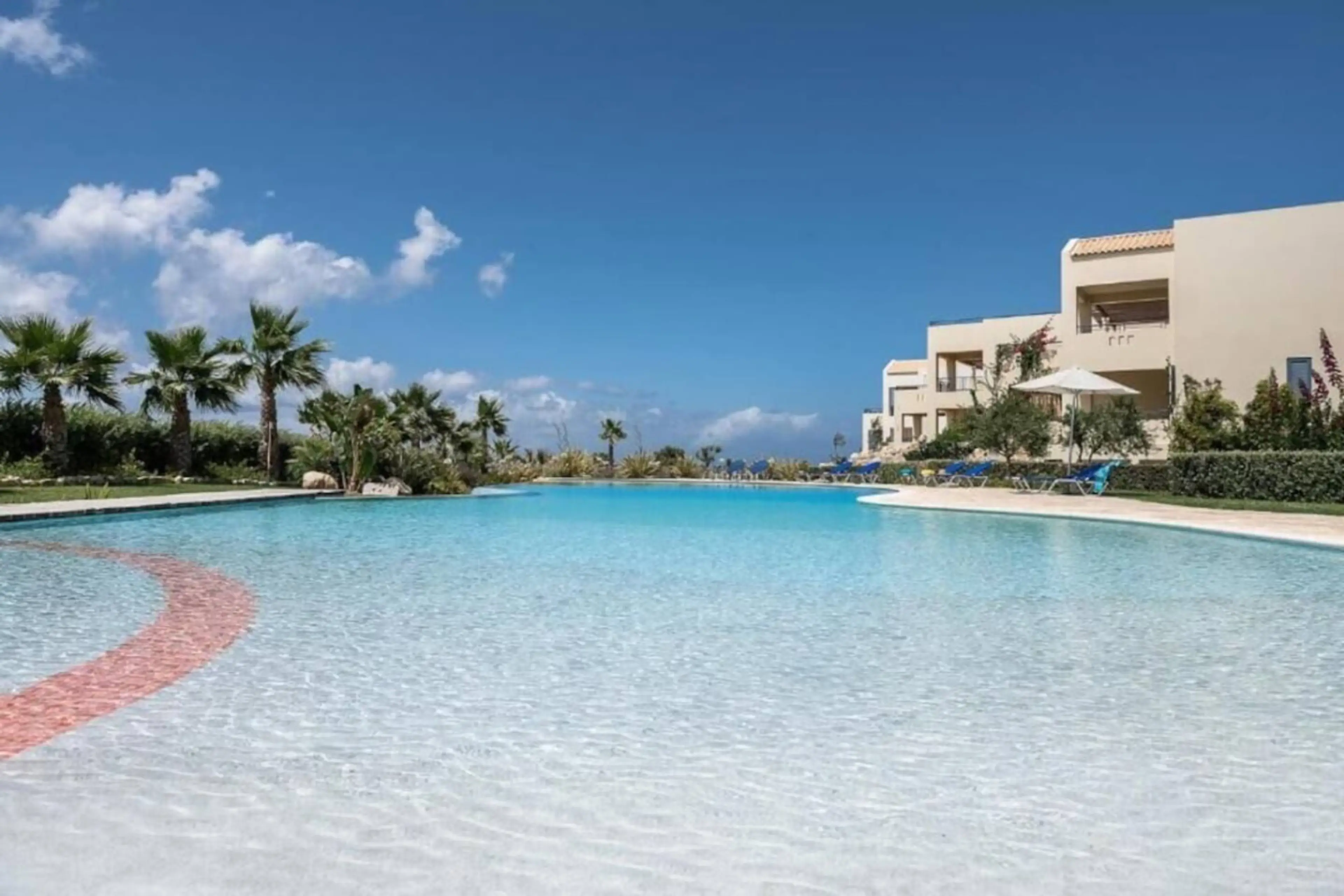 Stunning lagoon-style pool, surrounded by swaying palms and vibrant gardens. Whether you're lounging on a sunbed or strolling along the wooden bridge, every moment here feels like a tropical escape