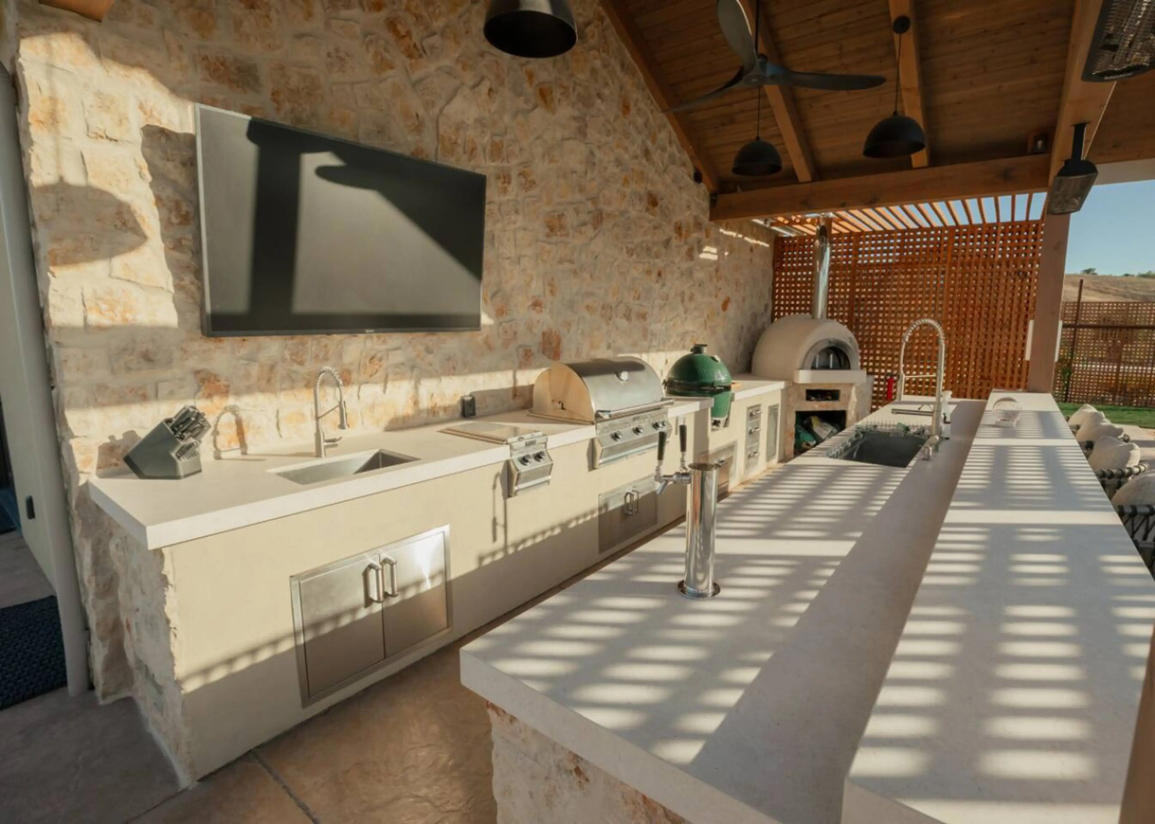 This rustic modern outdoor kitchen and bar pair stone accents with stainless appliances to create a refined space for cooking, sipping, and enjoying good company.