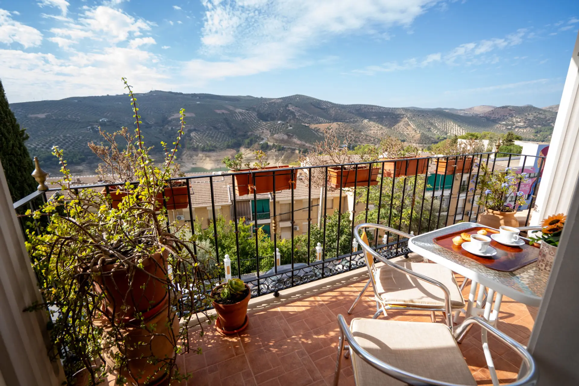 Vista amplia de la terraza con paisaje montañoso al fondo. La luz del día realza los colores cálidos del entorno, creando una sensación de bienestar y calma. Ideal para disfrutar del clima y las vistas de Iznájar.
