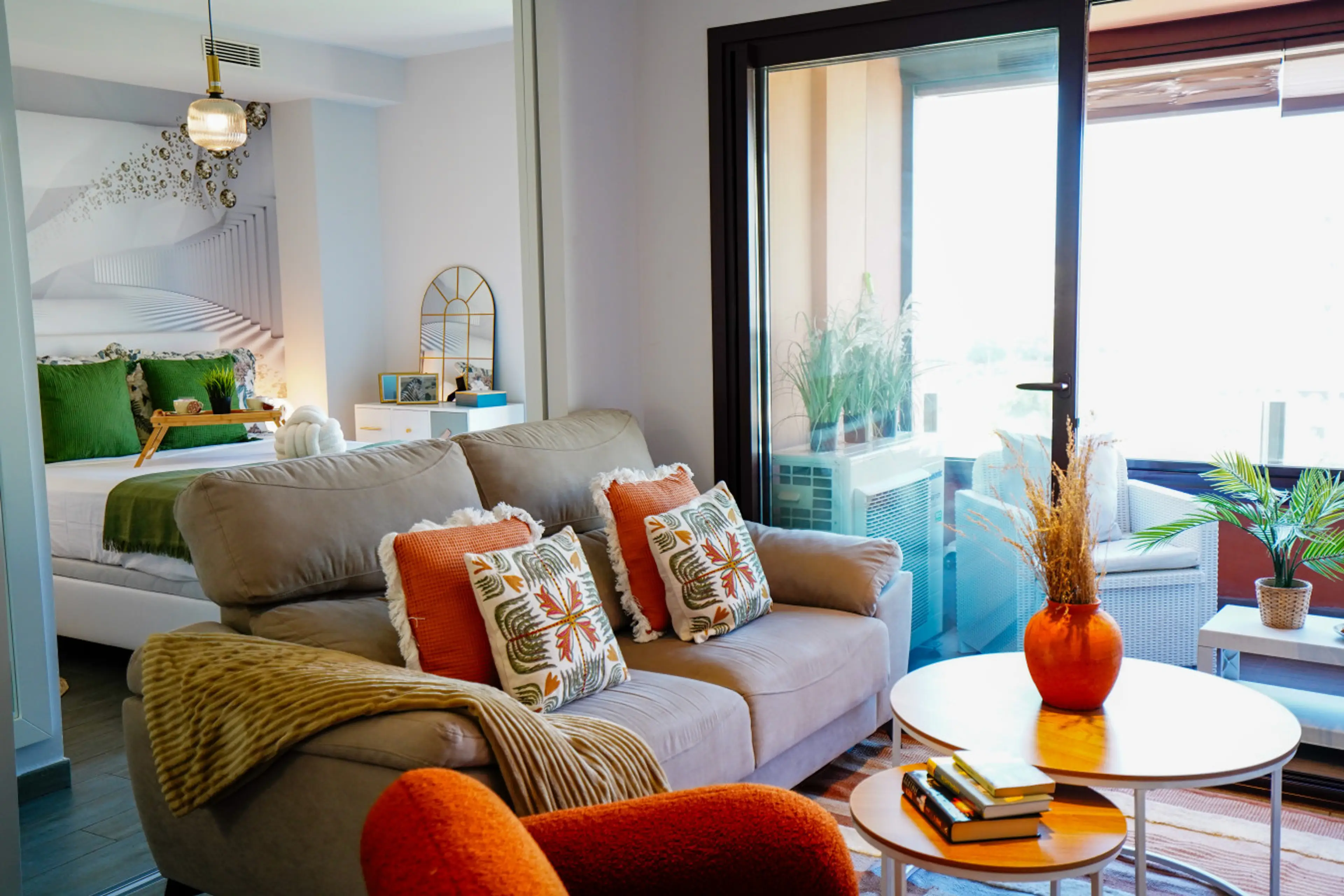 Zona de estar amplia y confortable con sofás en tonos neutros y detalles decorativos modernos. Las grandes ventanas permiten la entrada de abundante luz natural. Ideal para relajarse tras un día de paseo o trabajo.