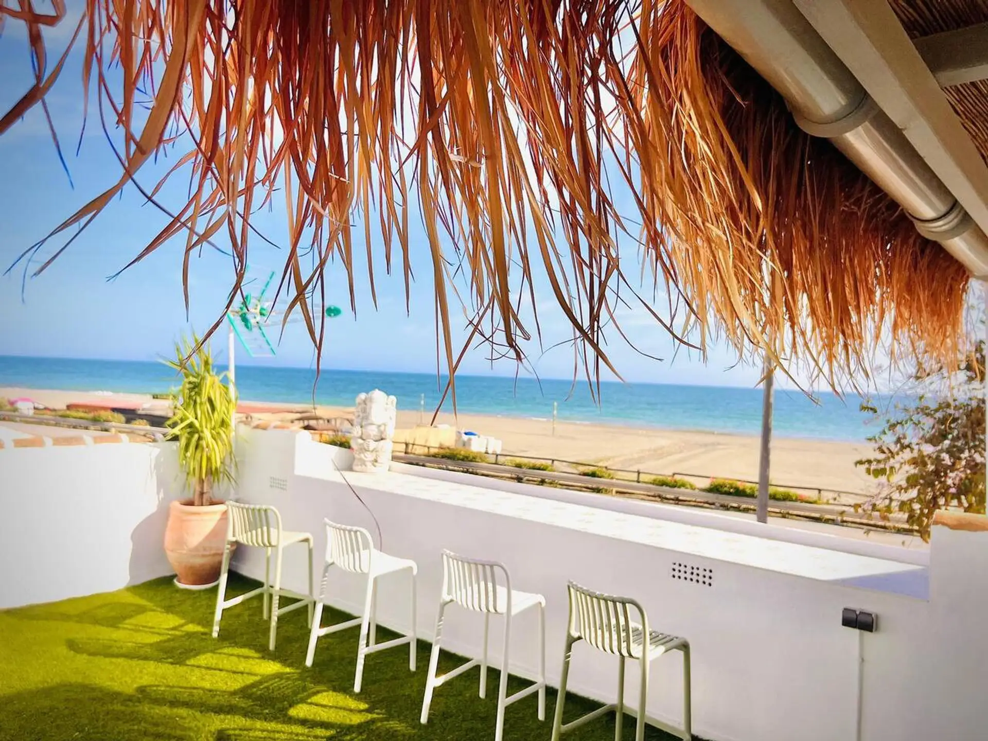 ☀️ Comedor exterior bajo un techo de palma, con vistas al Mediterráneo y una atmósfera relajada y natural.